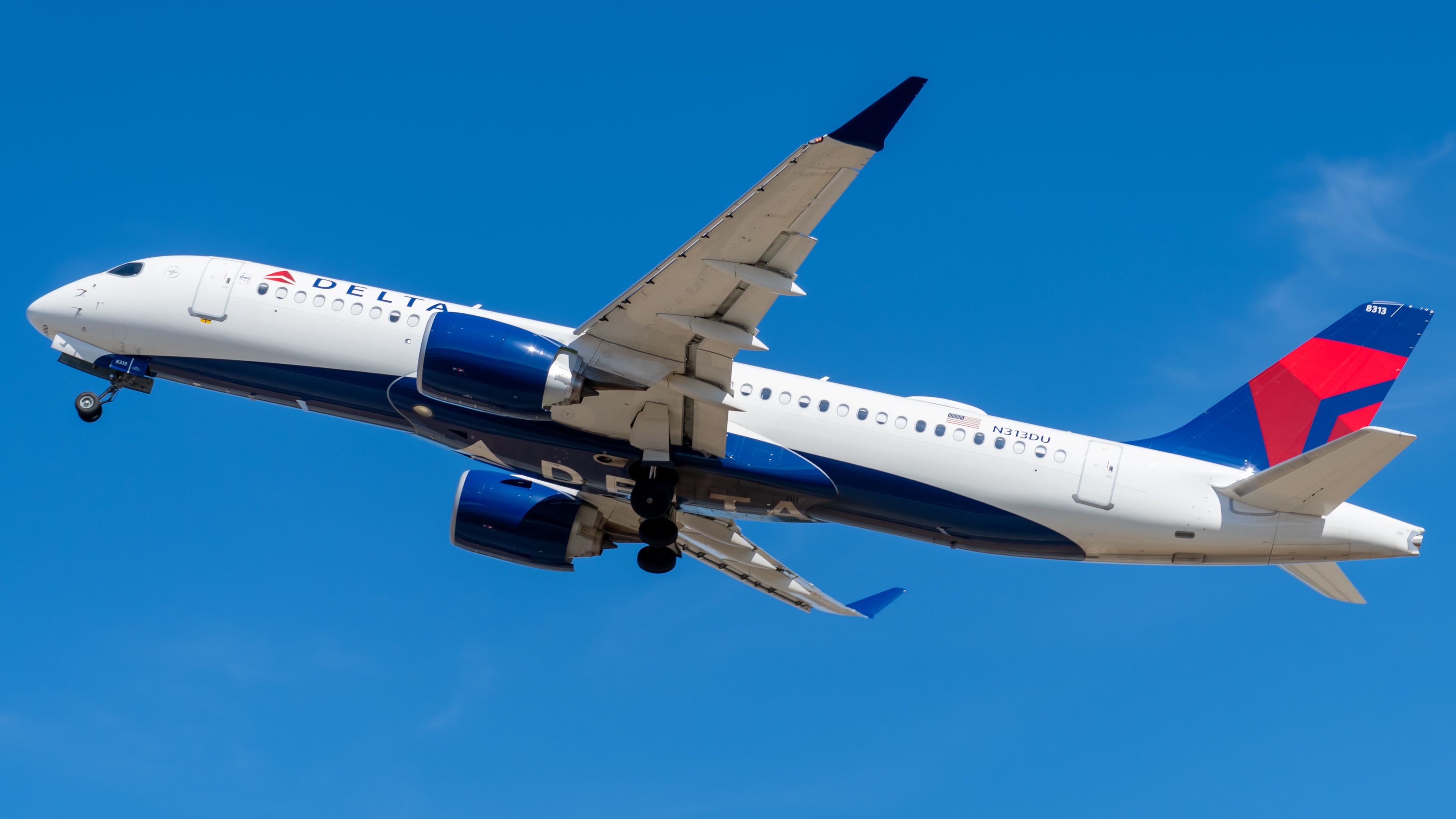 A Delta Air Lines Airbus A220 flying in the sky.