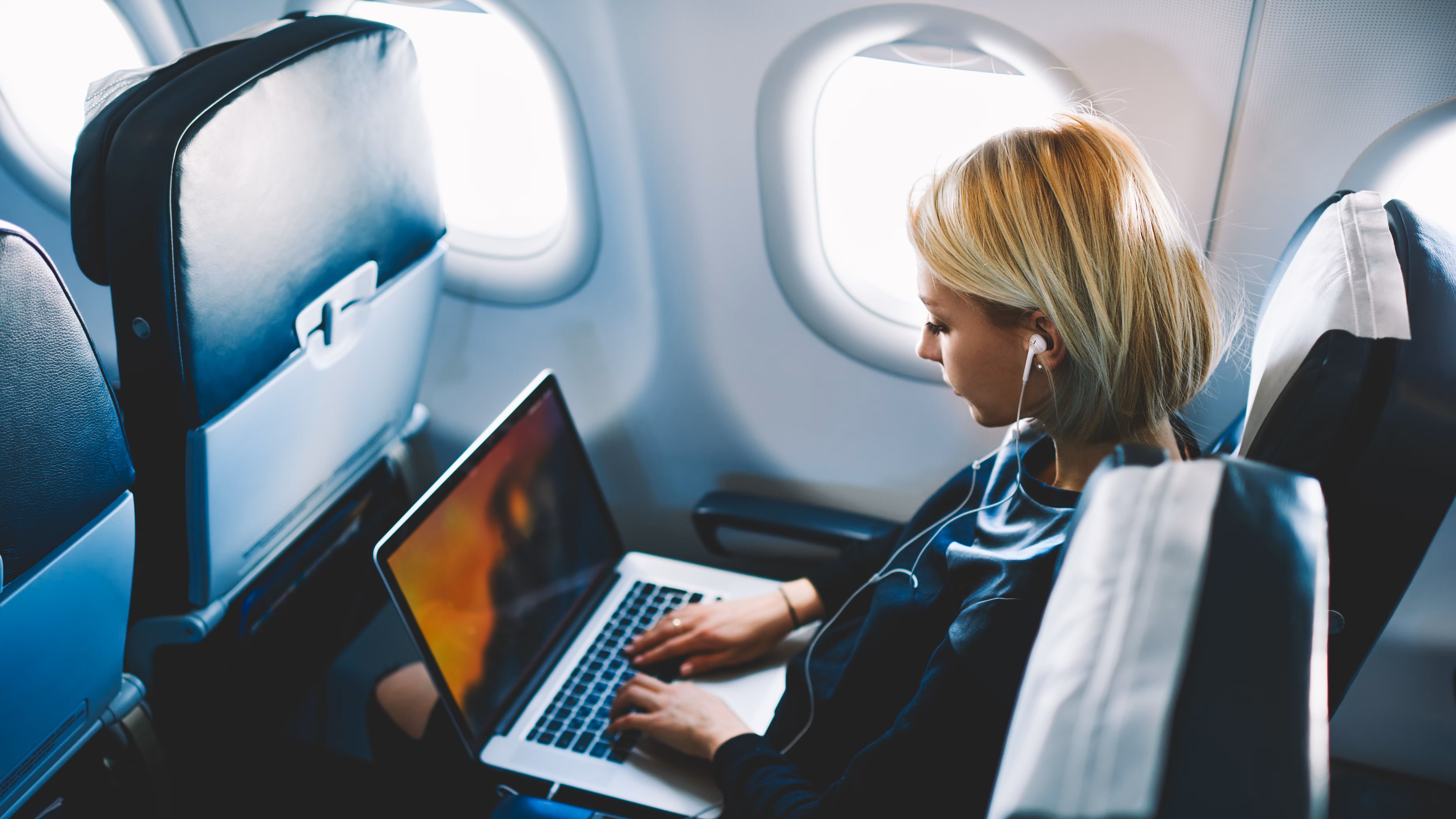A woman using her laptop on an airplane.
