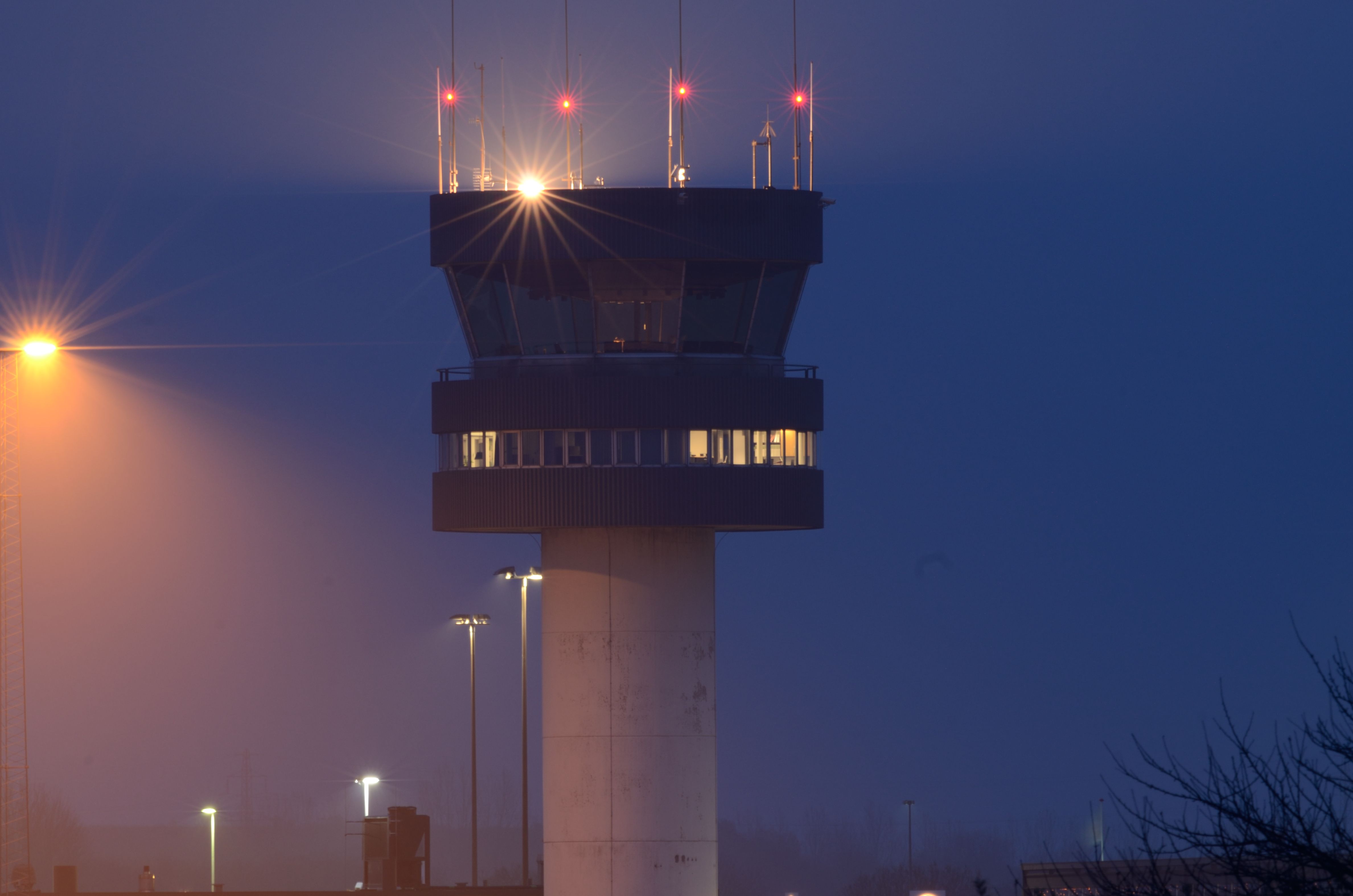 An airport control tower lighted at night.