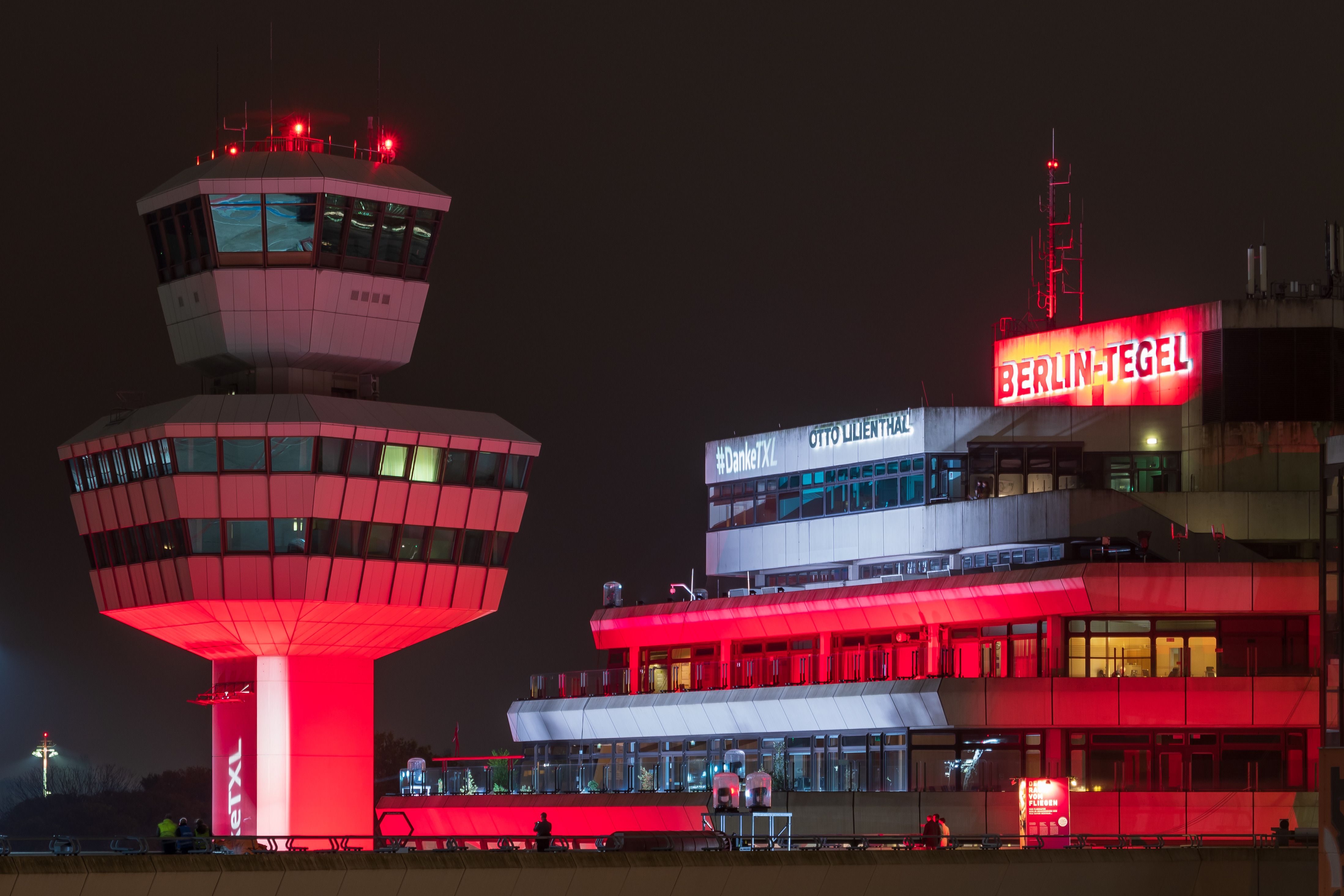 A photo of the control tower and terminal building of Berlin Tegel airport at night.