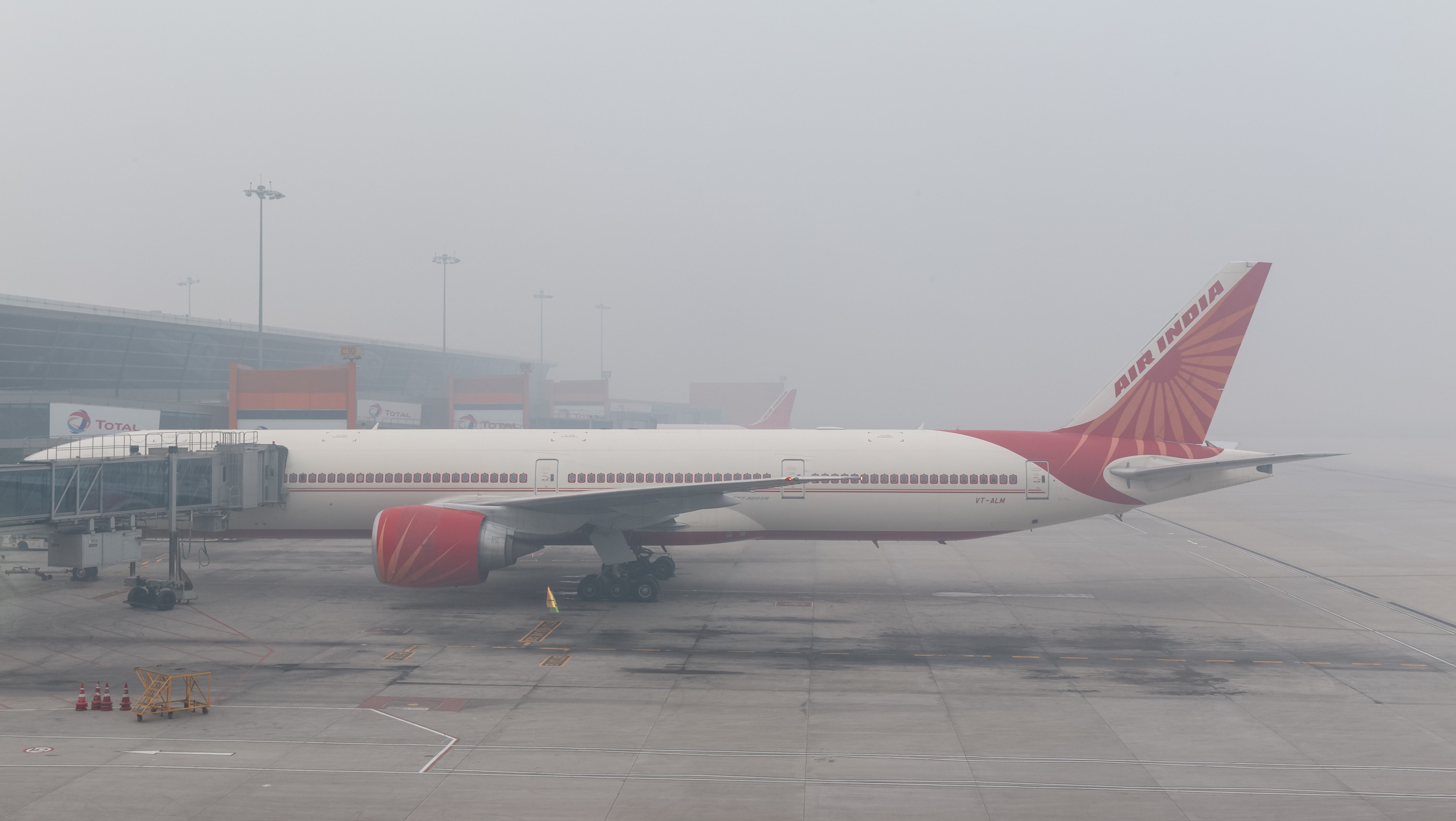 An Air India Boeing 777 aircraft parked at Delhi Airport on a foggy day.