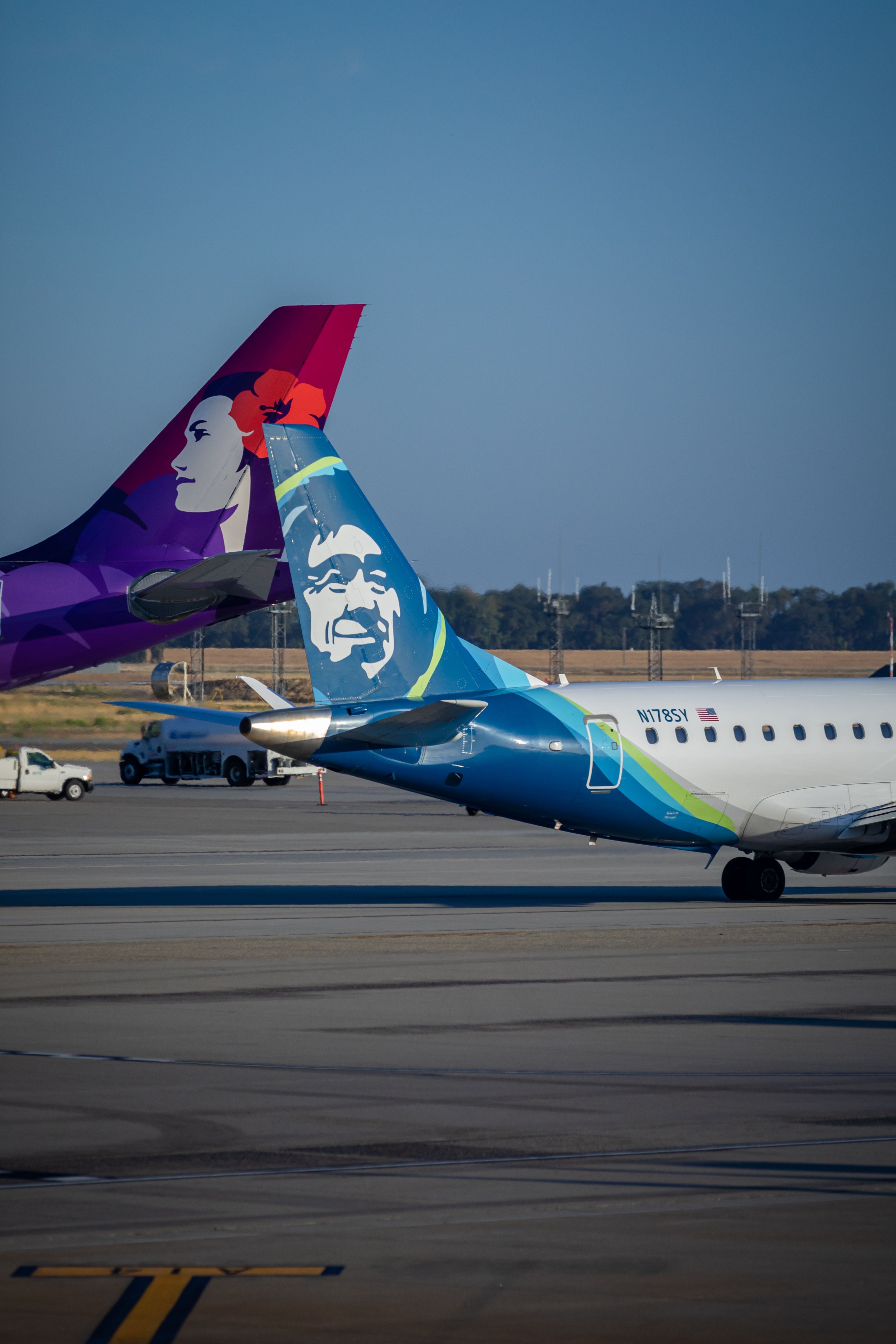 shutterstock_2121442103 - Hawaiian Airlines A330 tail and Alaska Air Group E175 tail