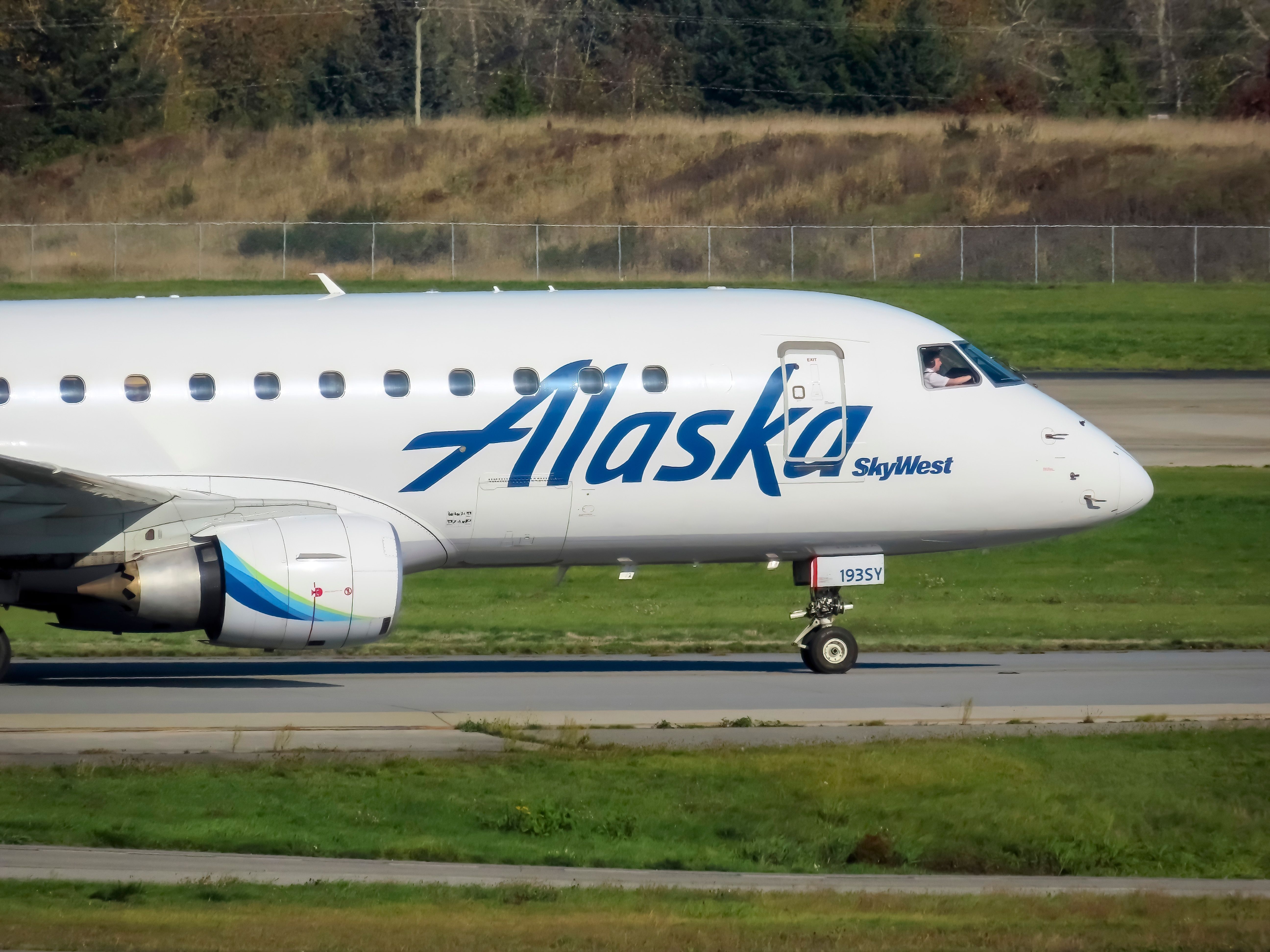 A detailed shot captures the frontal view of an Alaska Skywest airplane against the backdrop of the fall season.