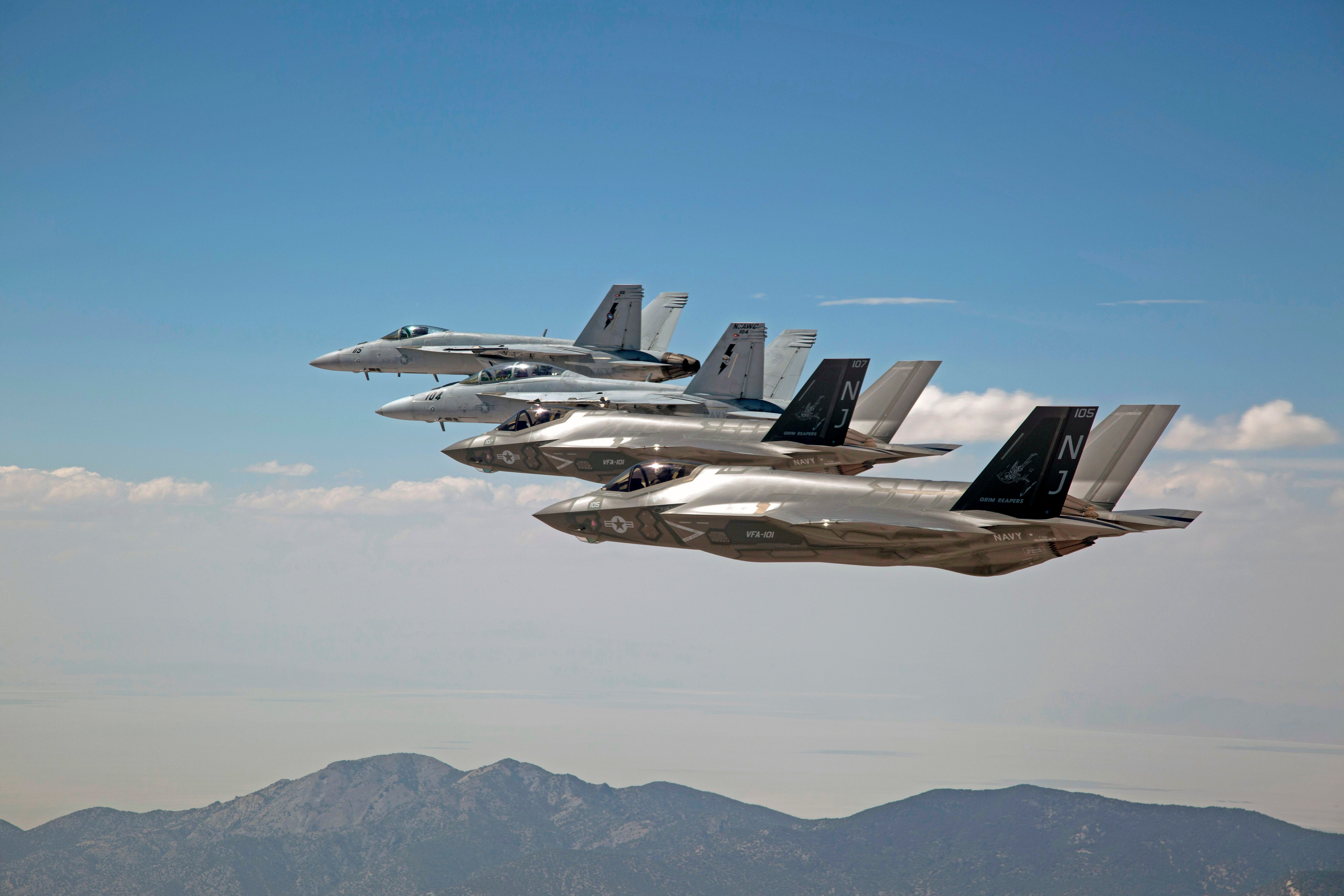 Several F-35Cs Lightning II and F/A-18F Super Hornets flying in the sky.