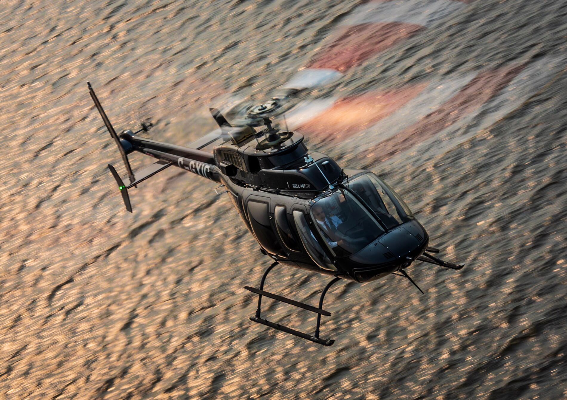 A Bell 407GXI flying over water.