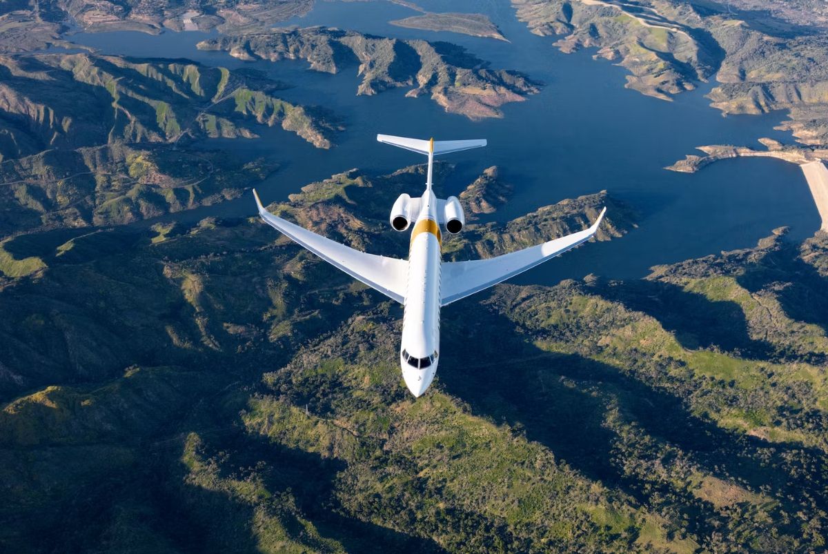 A Bombardier Global 7500 flying over mountainous terrain.