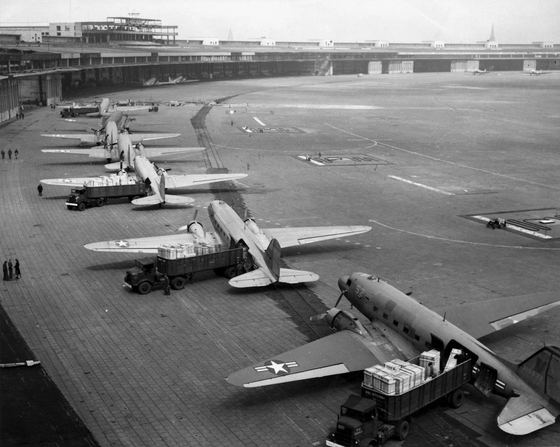 Several C-47 Skytrains lined up on an airfield during the Berlin Airlift.