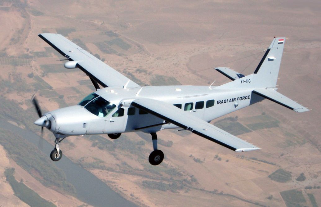 An Iraqi Air Force Cessna 208 flying over a desert.