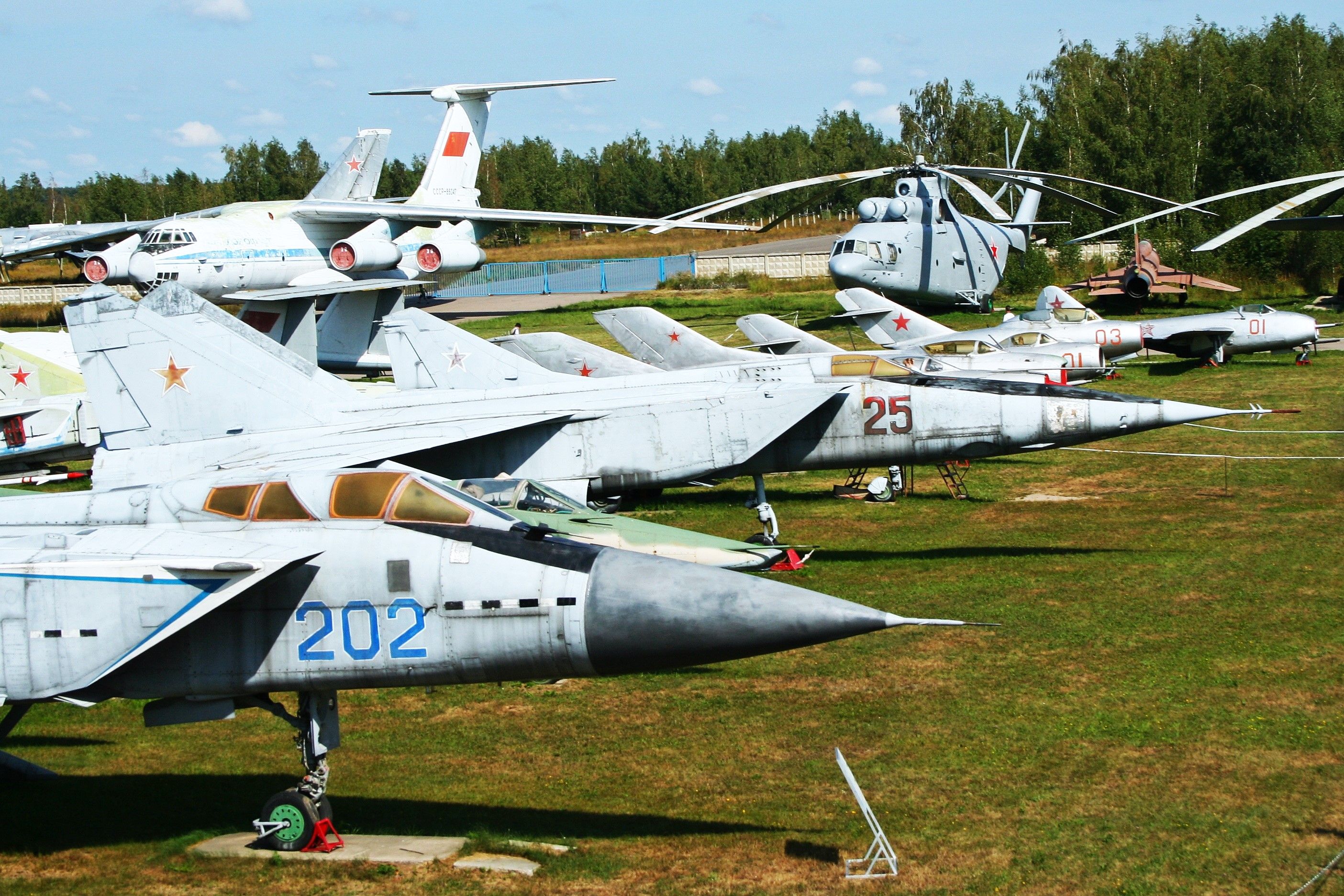 MiG_Alley_at_Monino_10060272626 - Taken from the Tu-144 access steps, this shot shows the main row of MiG fighters at Monino. From near to far:- MiG-31 '202 blue', MiG-27 '01 red', MiG-25R '25 red', MiG-23 '231 blue' MiG-21S '93 red', MiG-19PM '11 red' MiG-17 '01 red' MiG-15UTI '03 red' and MiG-9 '01 red'. Visible in the far background are a Tu-95 'Bear', an IL-76, a Mil-26 'Halo' and an Su-17 'Fitter'. Individual photos and details of all these aircraft appear elsewhere in this set. All are o