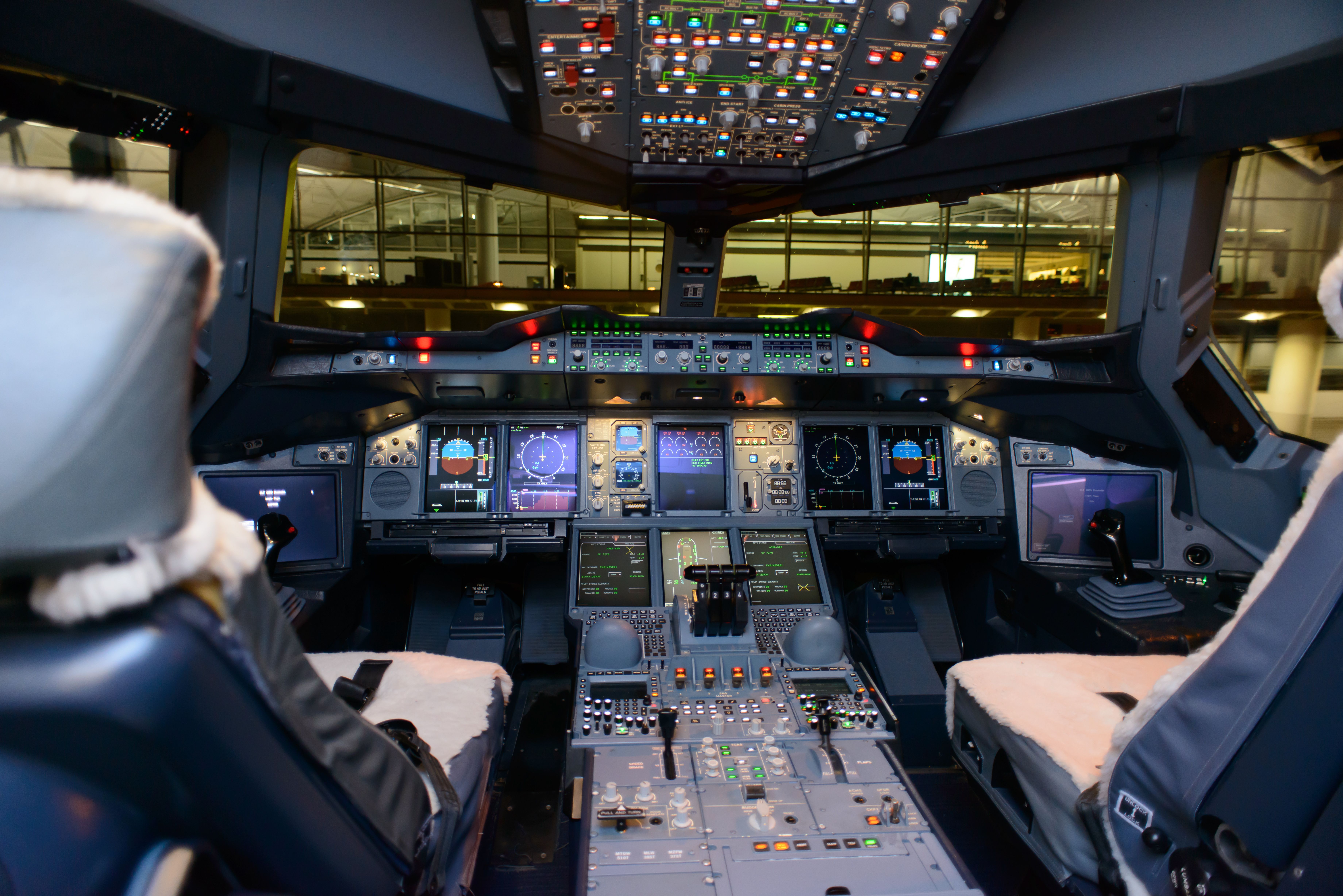 Inside the cockpit of an aircraft parked in front of an airport terminal.