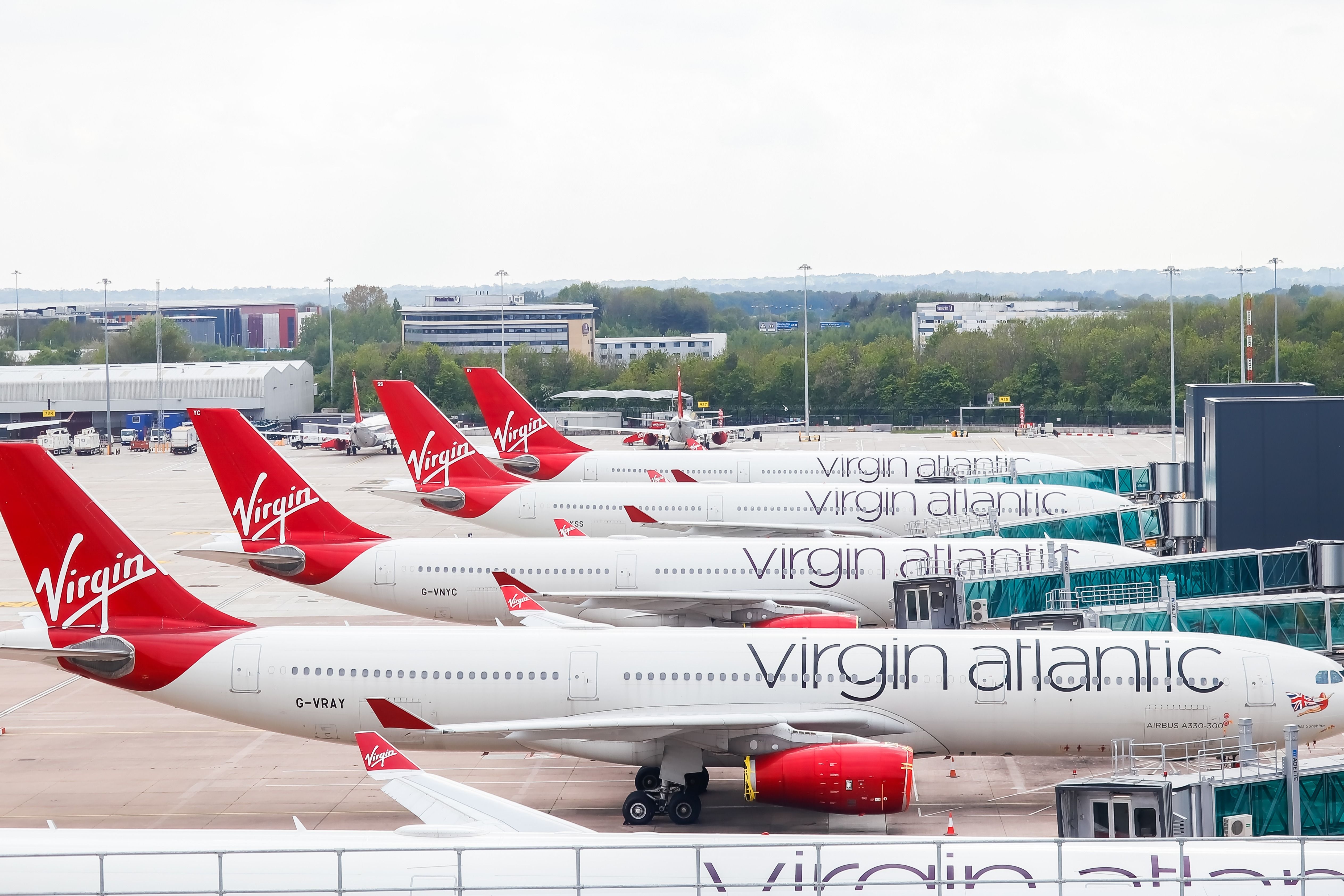 Several Virgin Atlantic Airbus aircraft parked side by side at an airport.