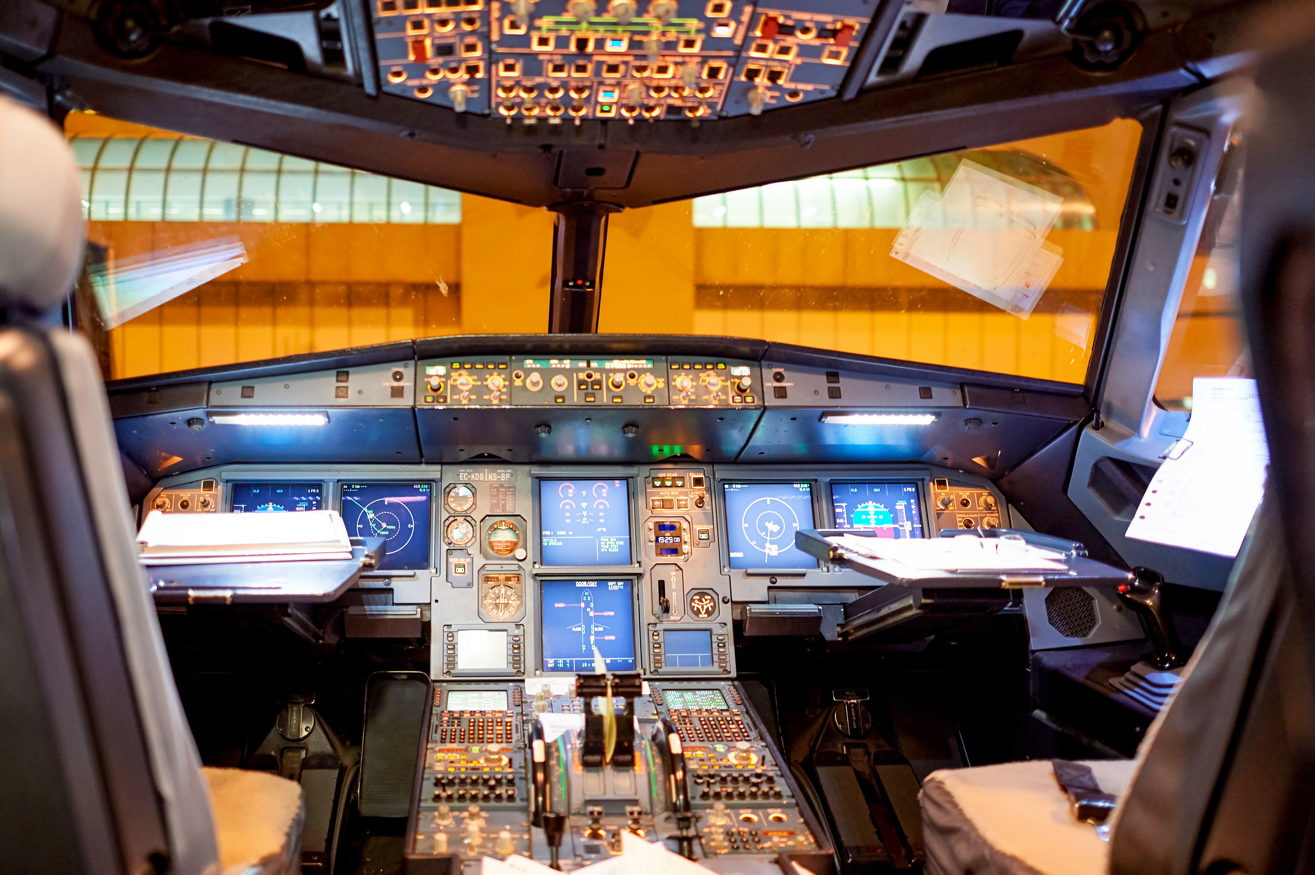 Inside the cockpit of an Airbus A320 parked in front of an airport terminal.