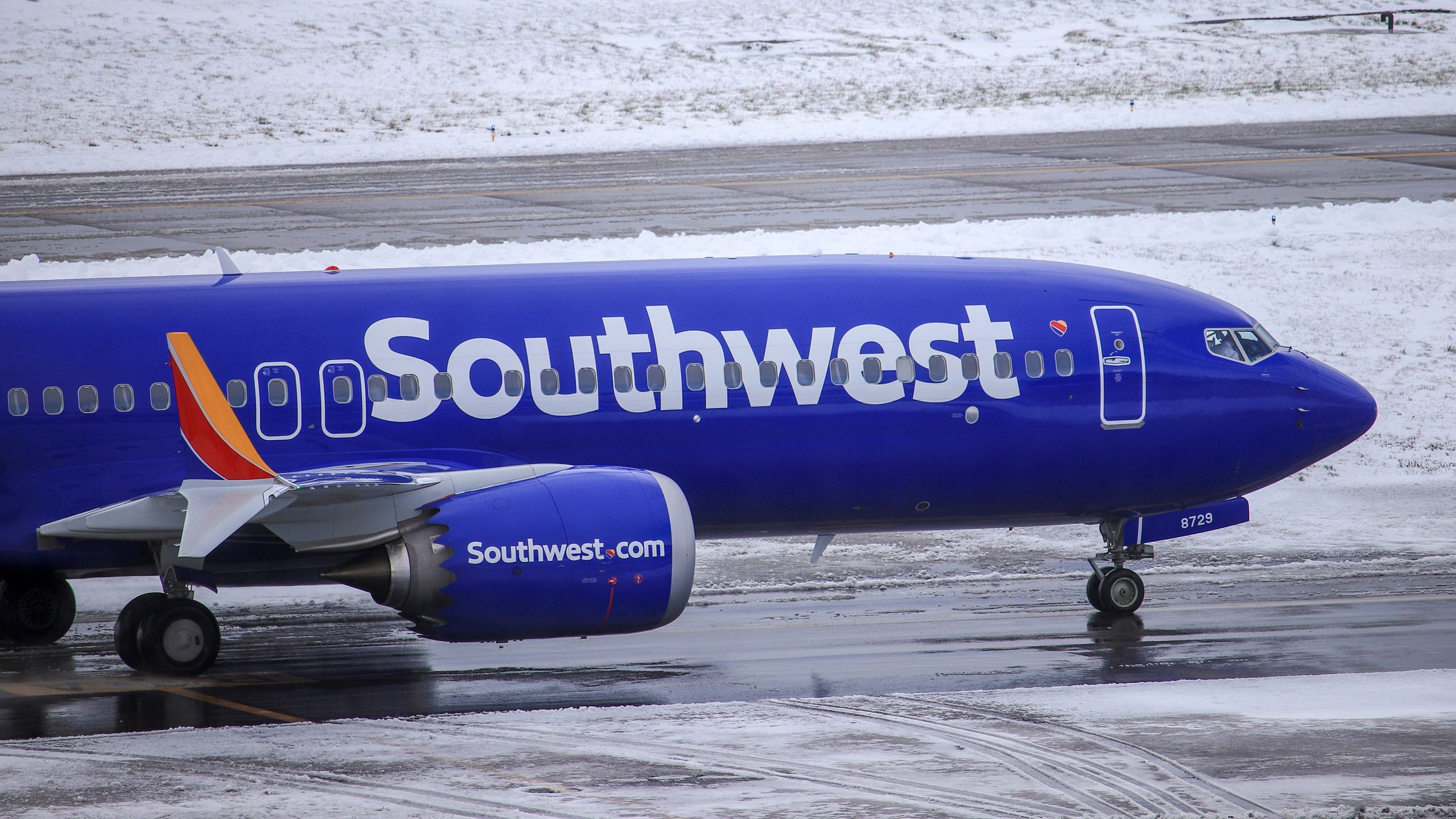 A Southwest Airlines Boeing 737 MAX 8 on a wet and snowy airport apron.