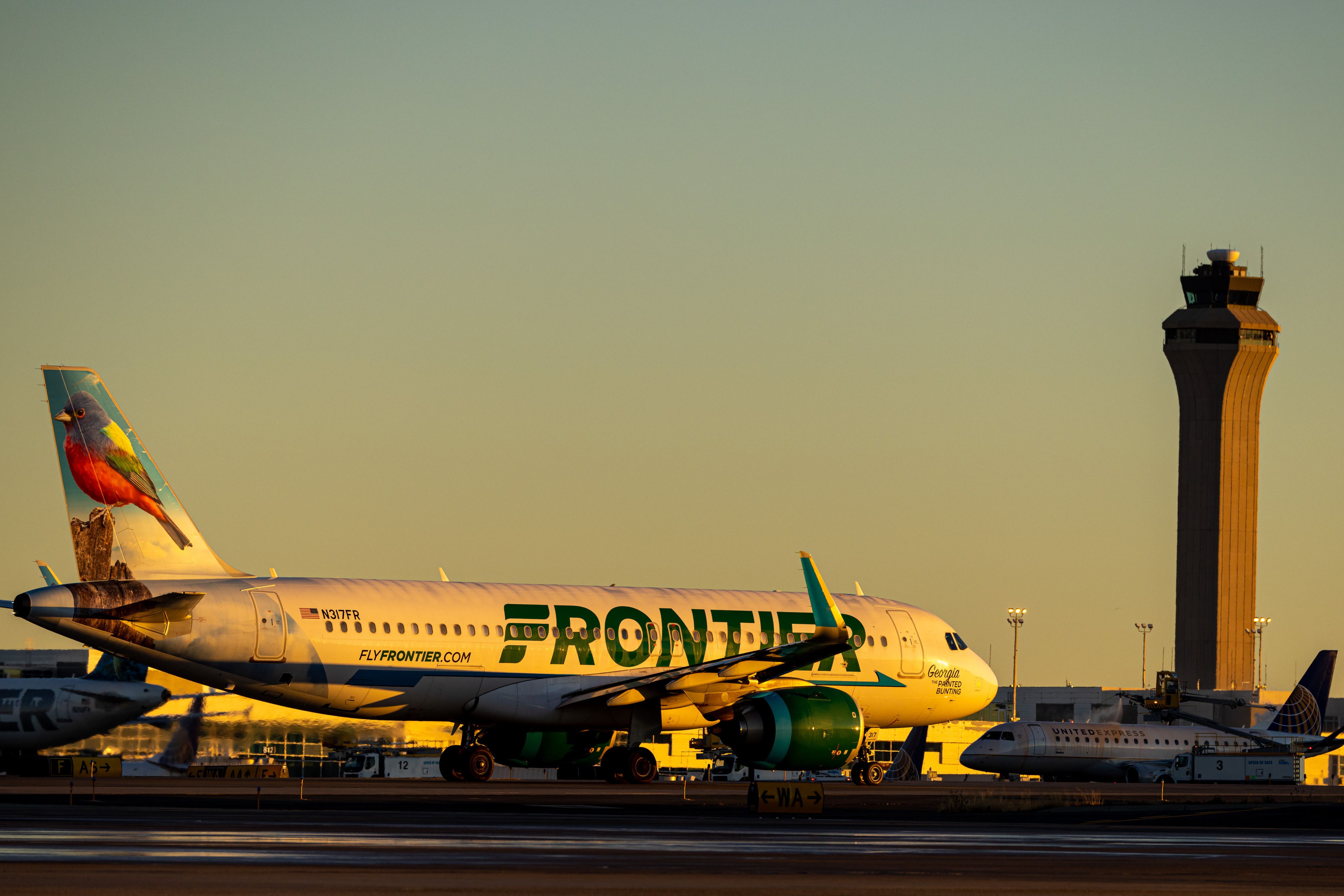 A Frontier Airlines plane in front of United Express operating for United Airlines at Denver International Airport