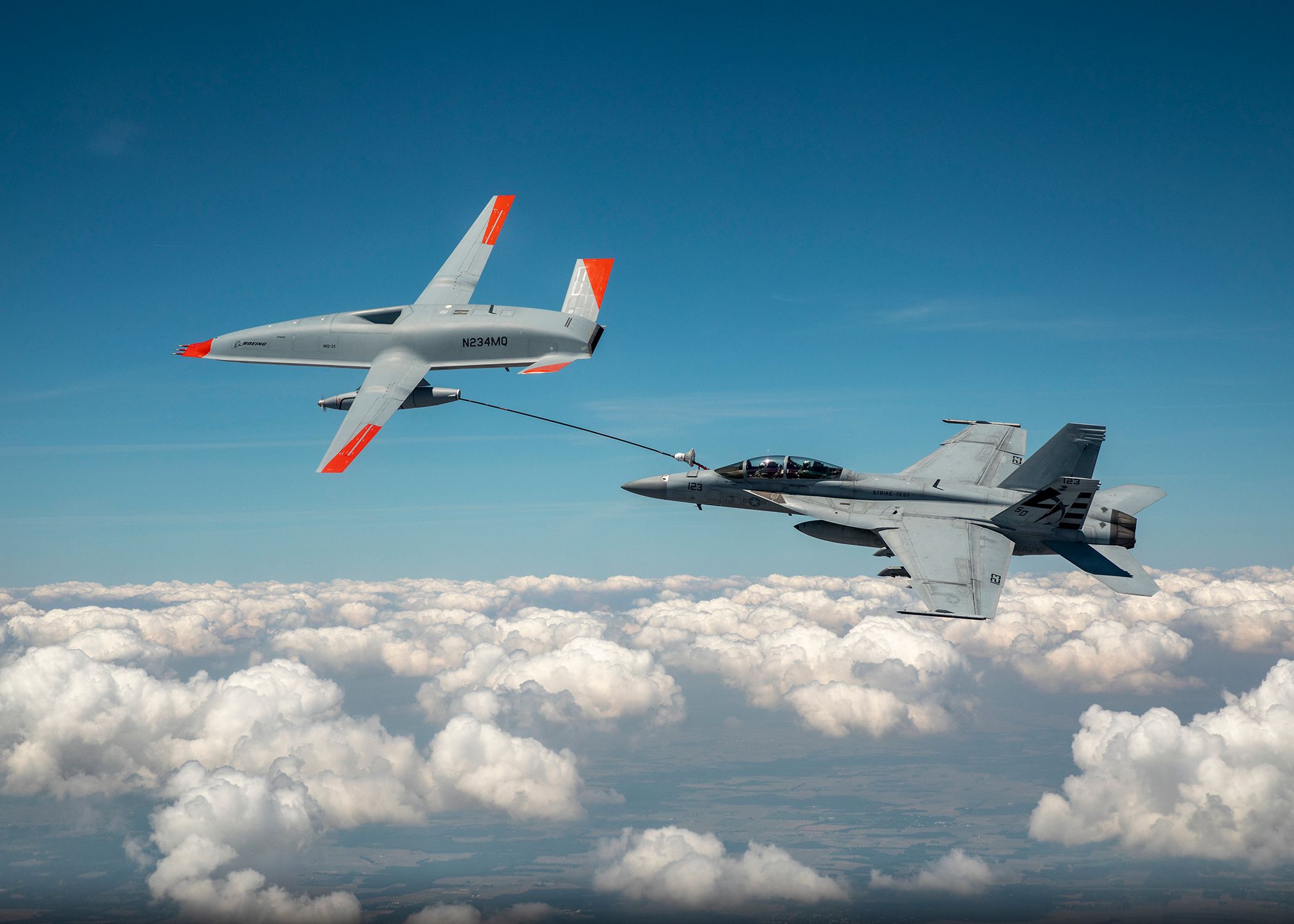 A U.S Navy Boeing MQ-25 Stingray refueling an F-18 above the clouds.