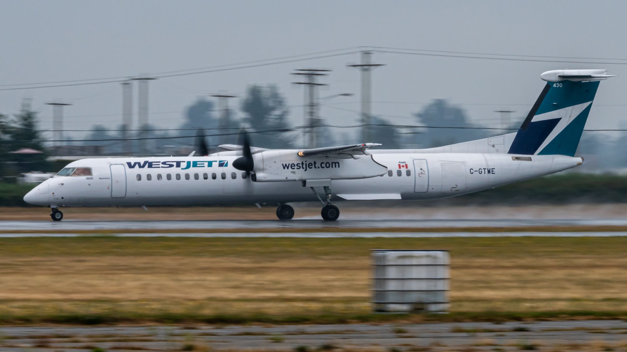 A Q400 of Westjet Encore Kicking Up Water on the Abbotsford Airport Runway