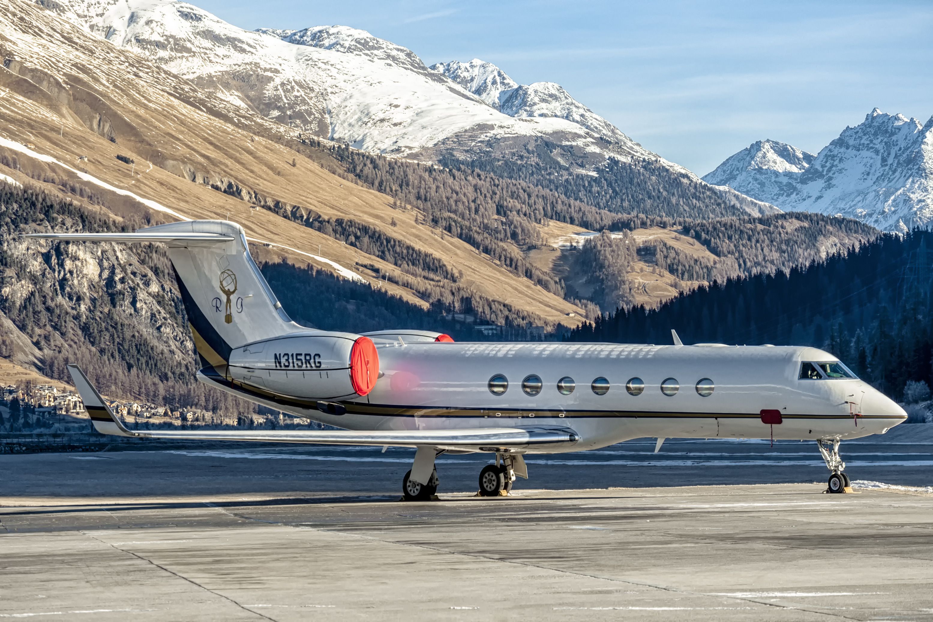 A Gulfstream G550 on an airport apron with mountains in the background. 