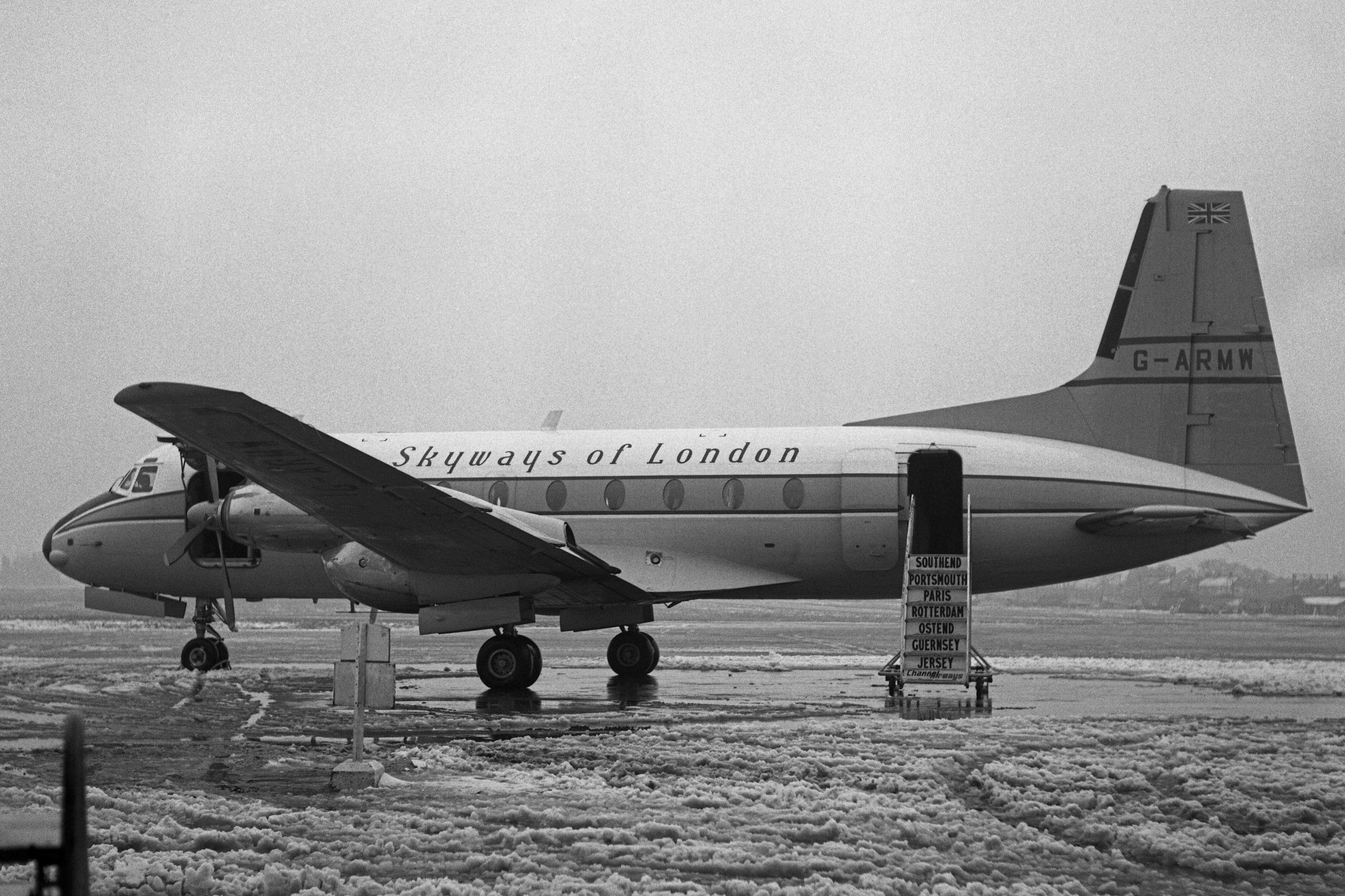 A Skyways Avro/HS 748 Parked on a snowy airport apron With its Stairs Deployed.