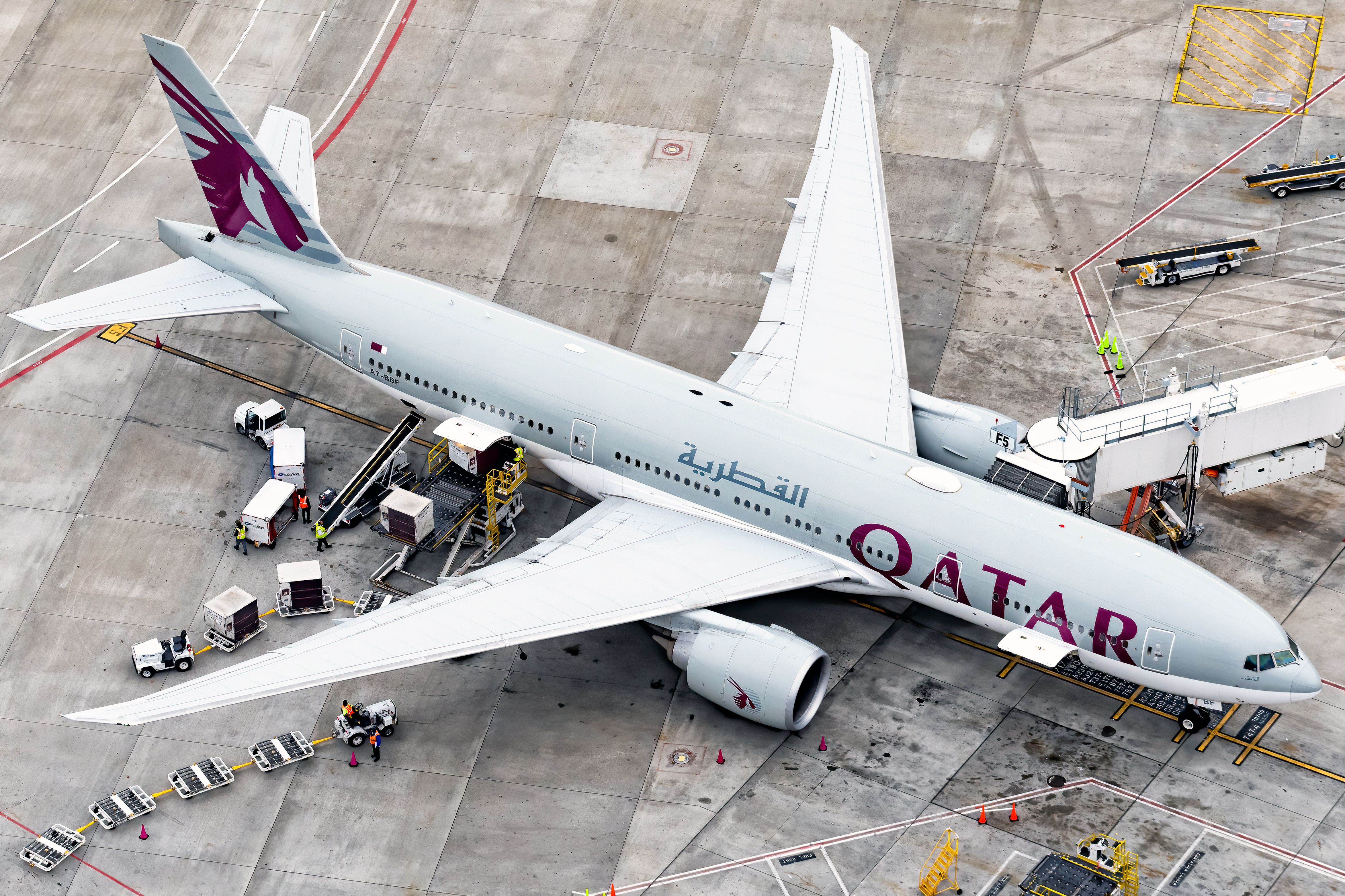 An aerial view of a Qatar Airways Boeing 777-200 on an airport apron.