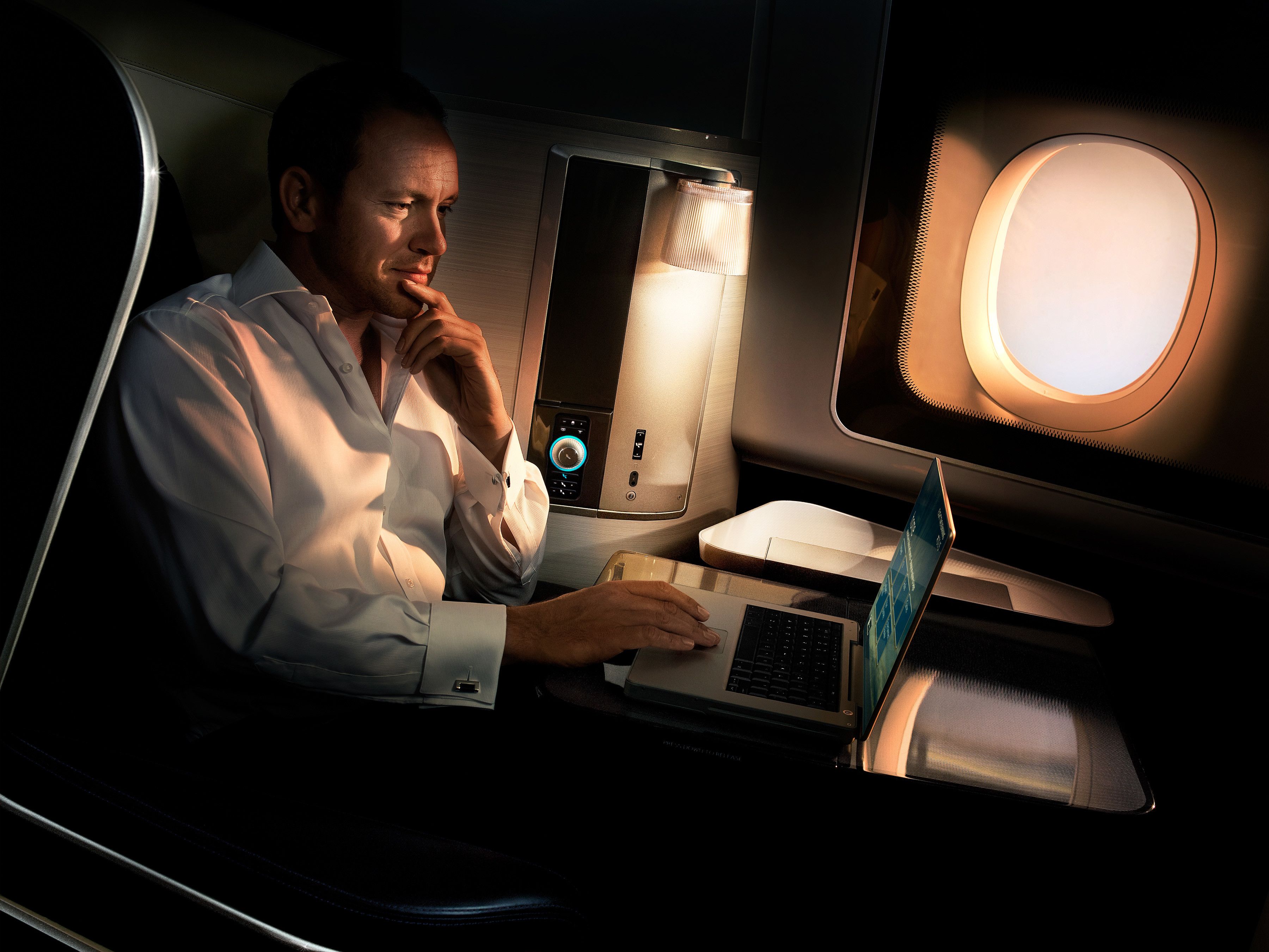 A Male Passenger Using his Laptop In A British Airways First Class Window Seat.
