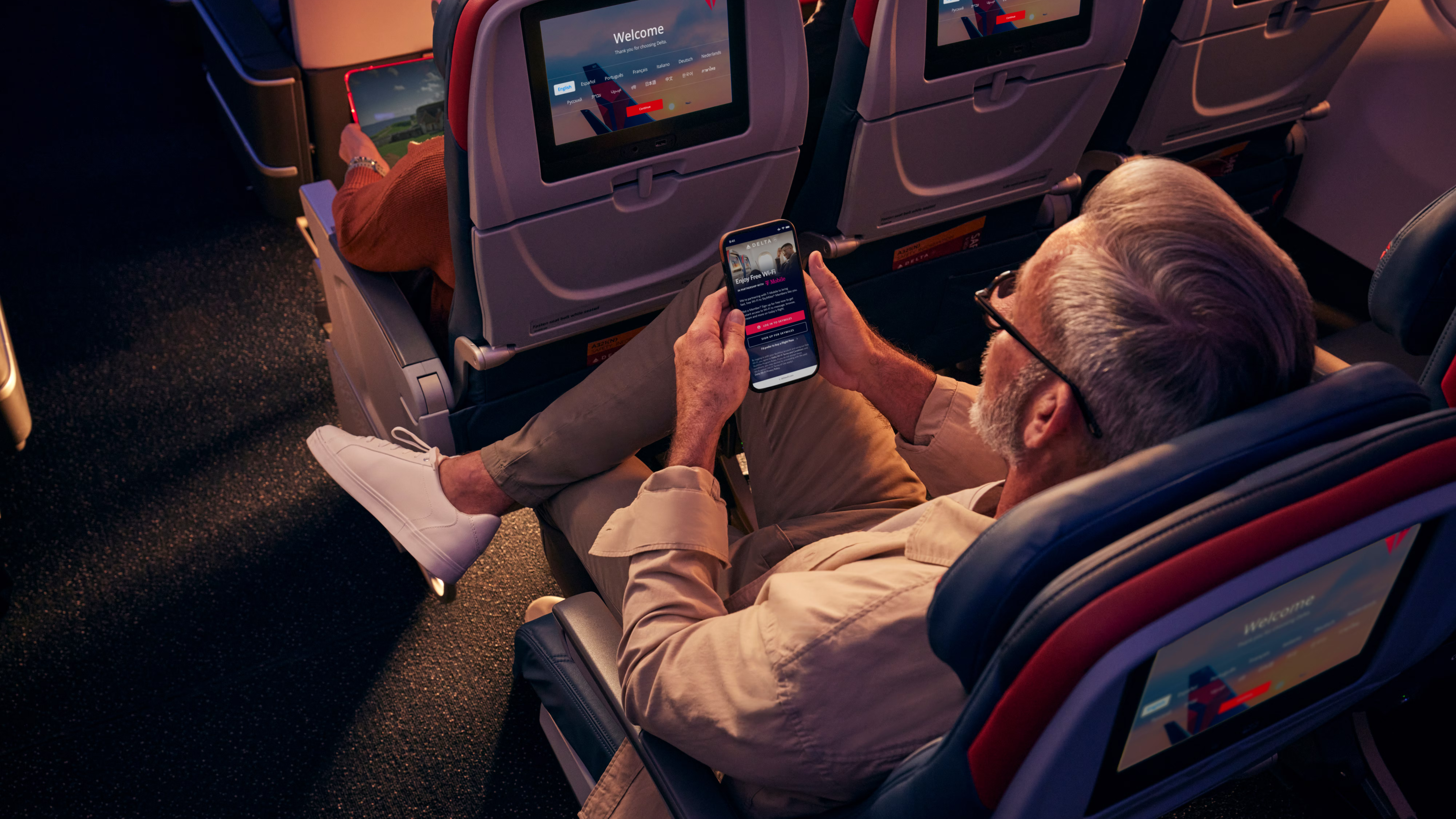 A passenger using his phone while sitting in Delta's Comfort Plus cabin.