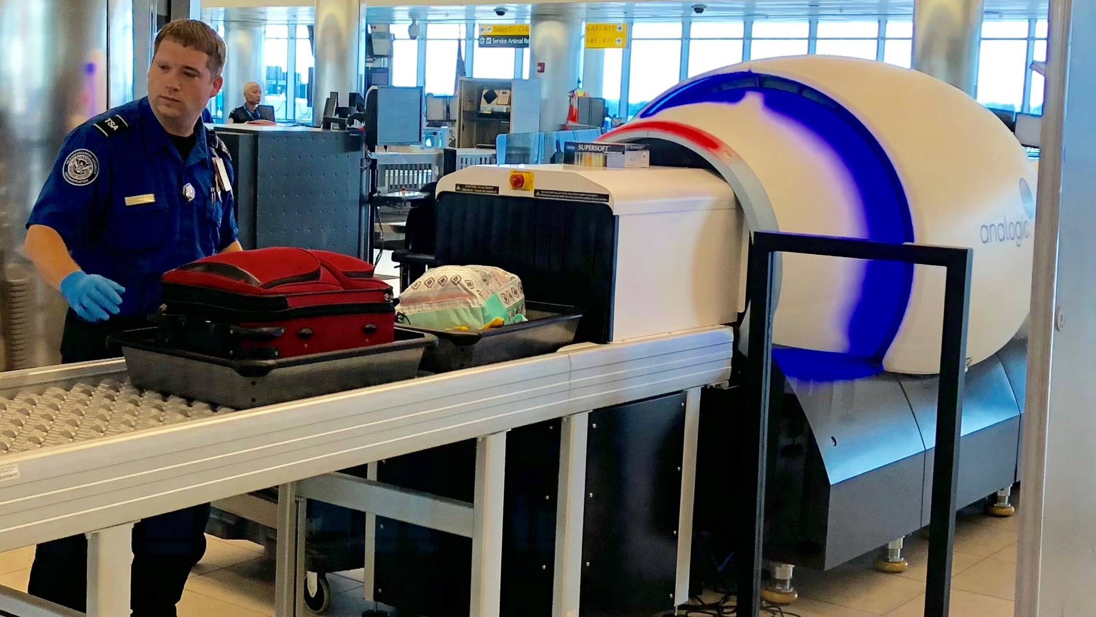 A TSA employee checking a screen as items go through an airport security CT scanner.