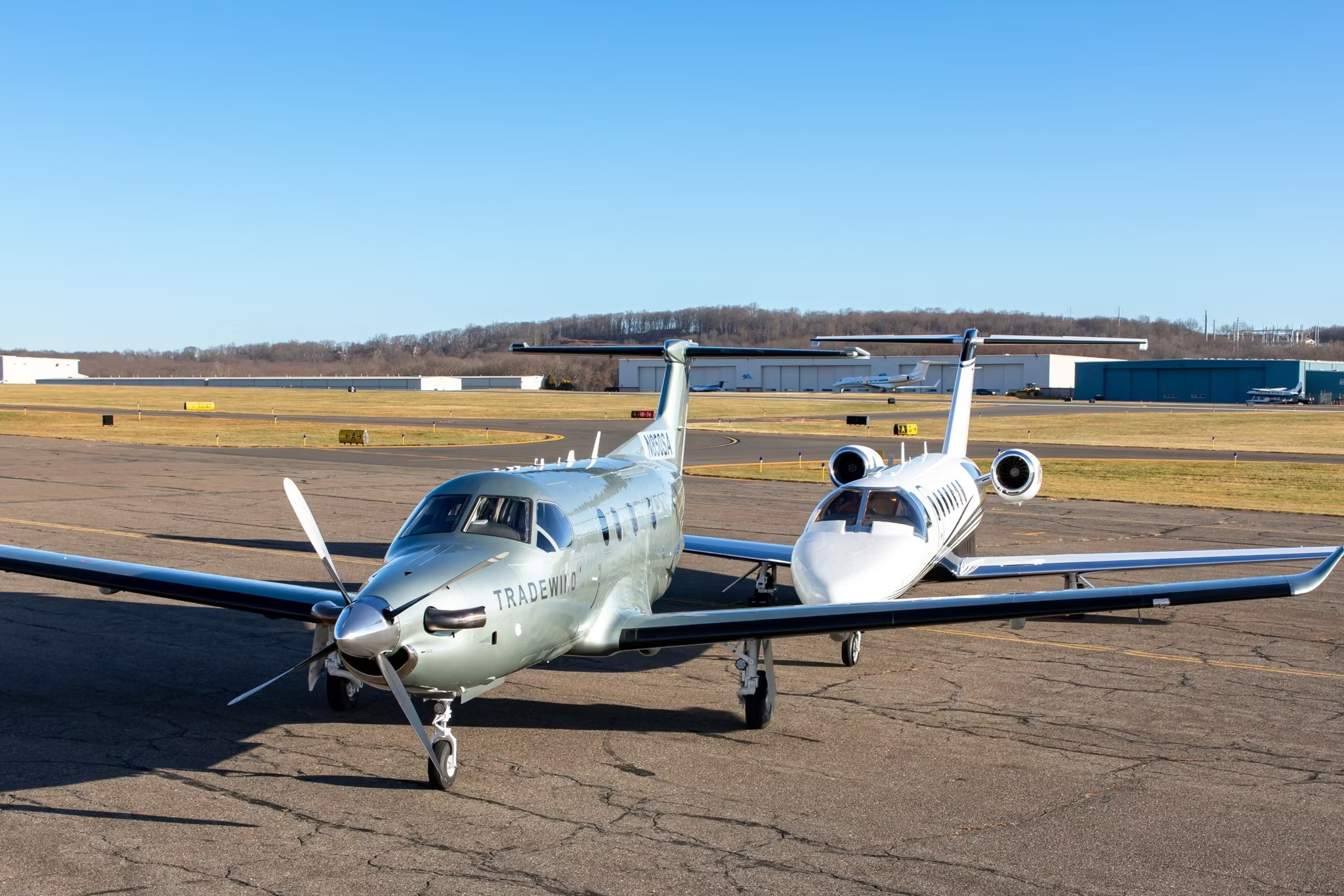 A Tradewind Aviation jet aircraft and turboprop parked side by side at an airport.