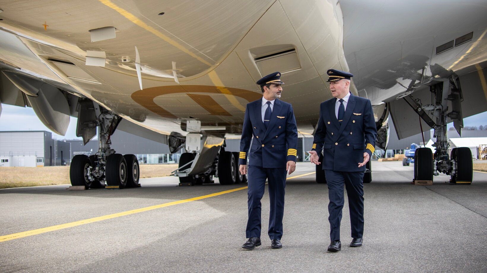 Two Etihad Airways pilots walking underneath an Airbus A380.