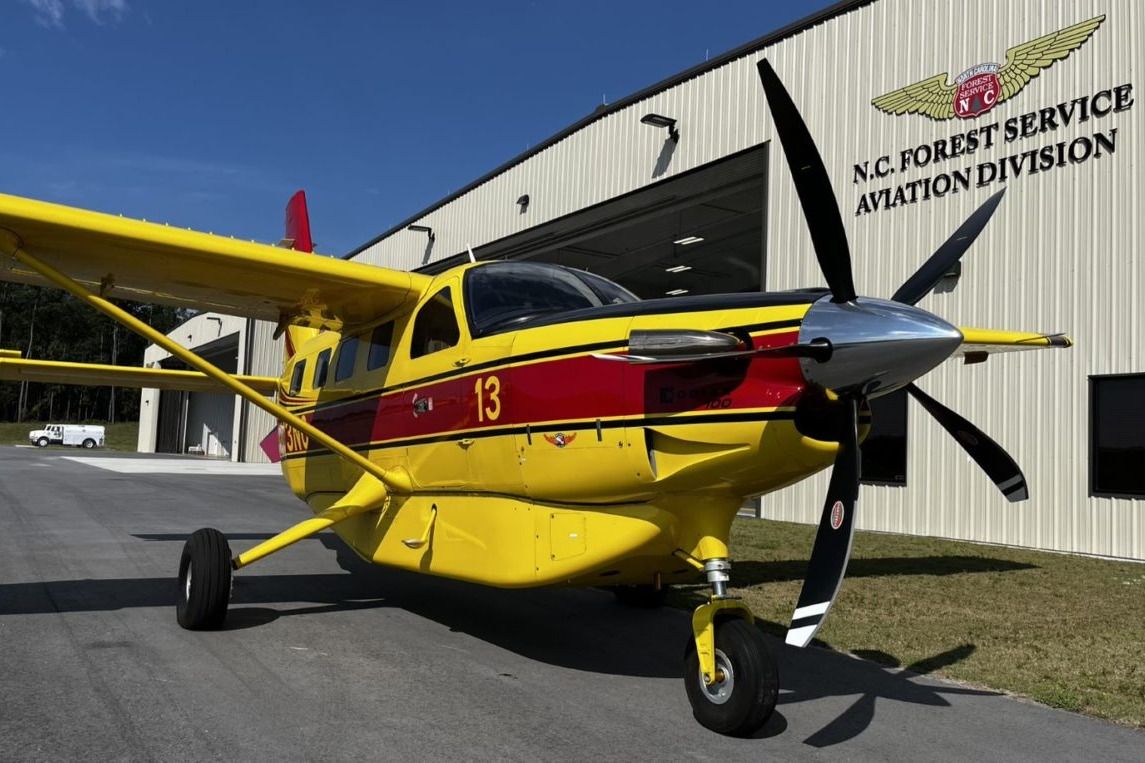 A North Carolina Forest Service Kodiak 100 parked outside of a hangar.