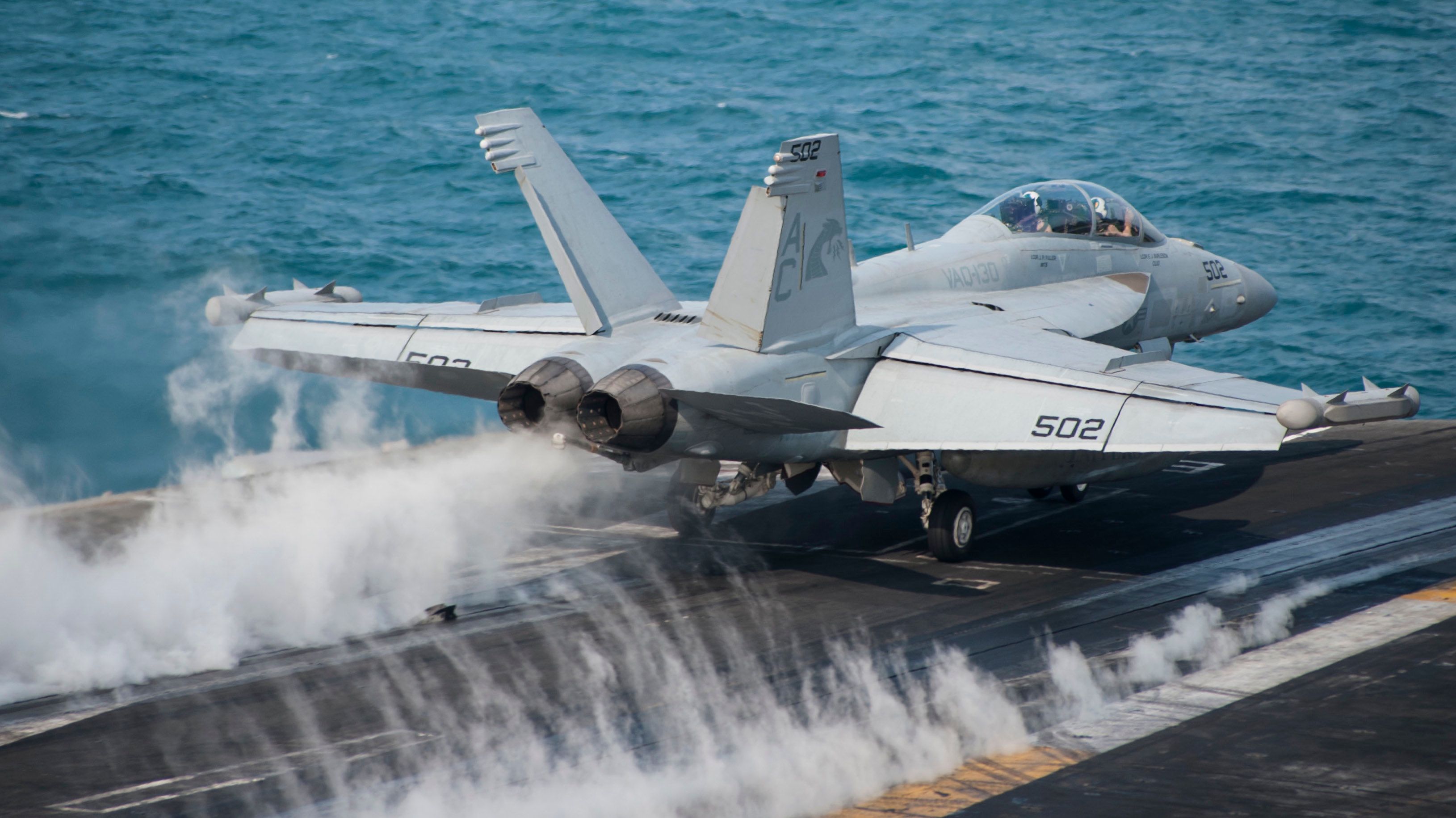 A US Navy Growler landing on an aircraft carrier.
