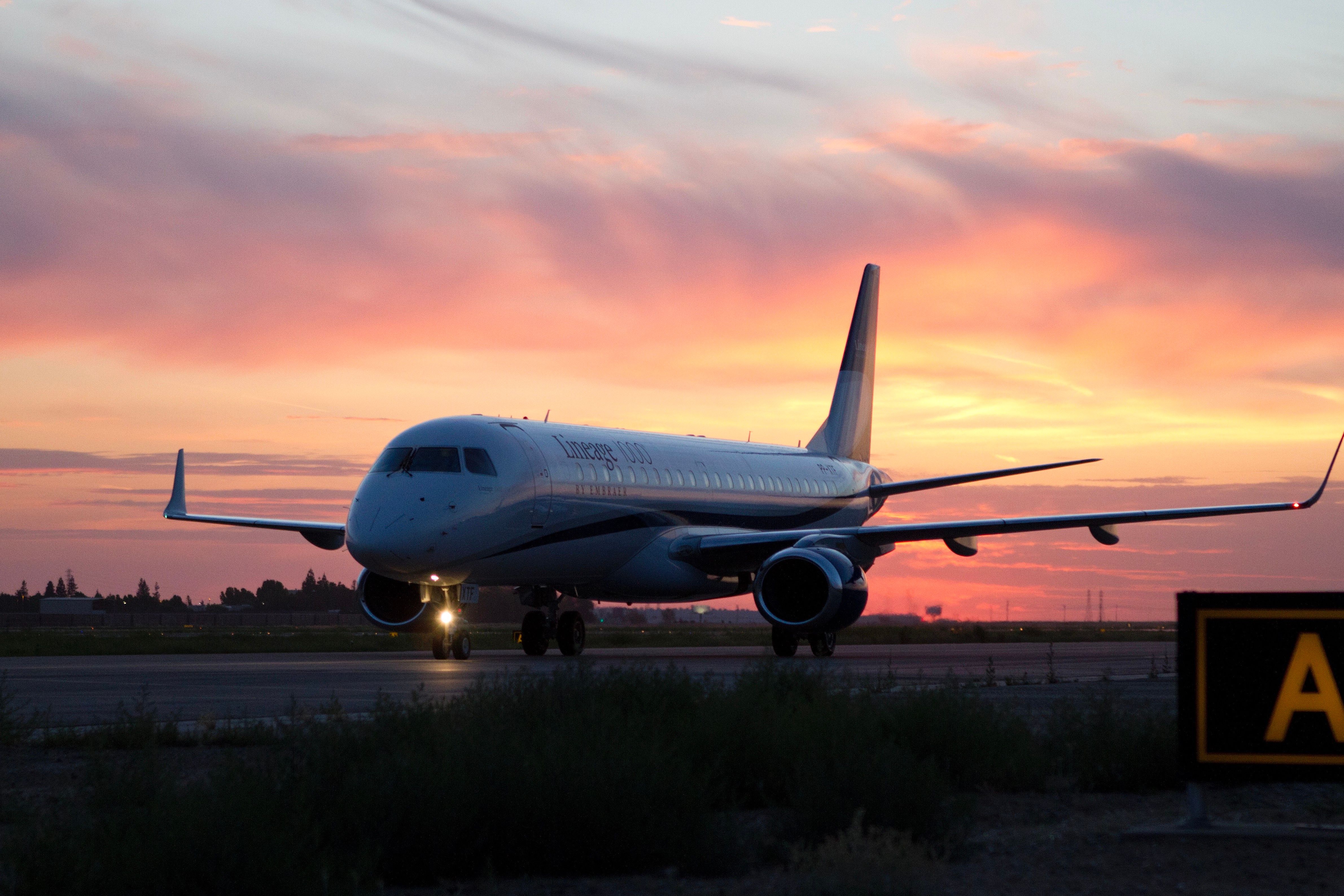 An Embraer Lineage 1000 on the ground during sunset.