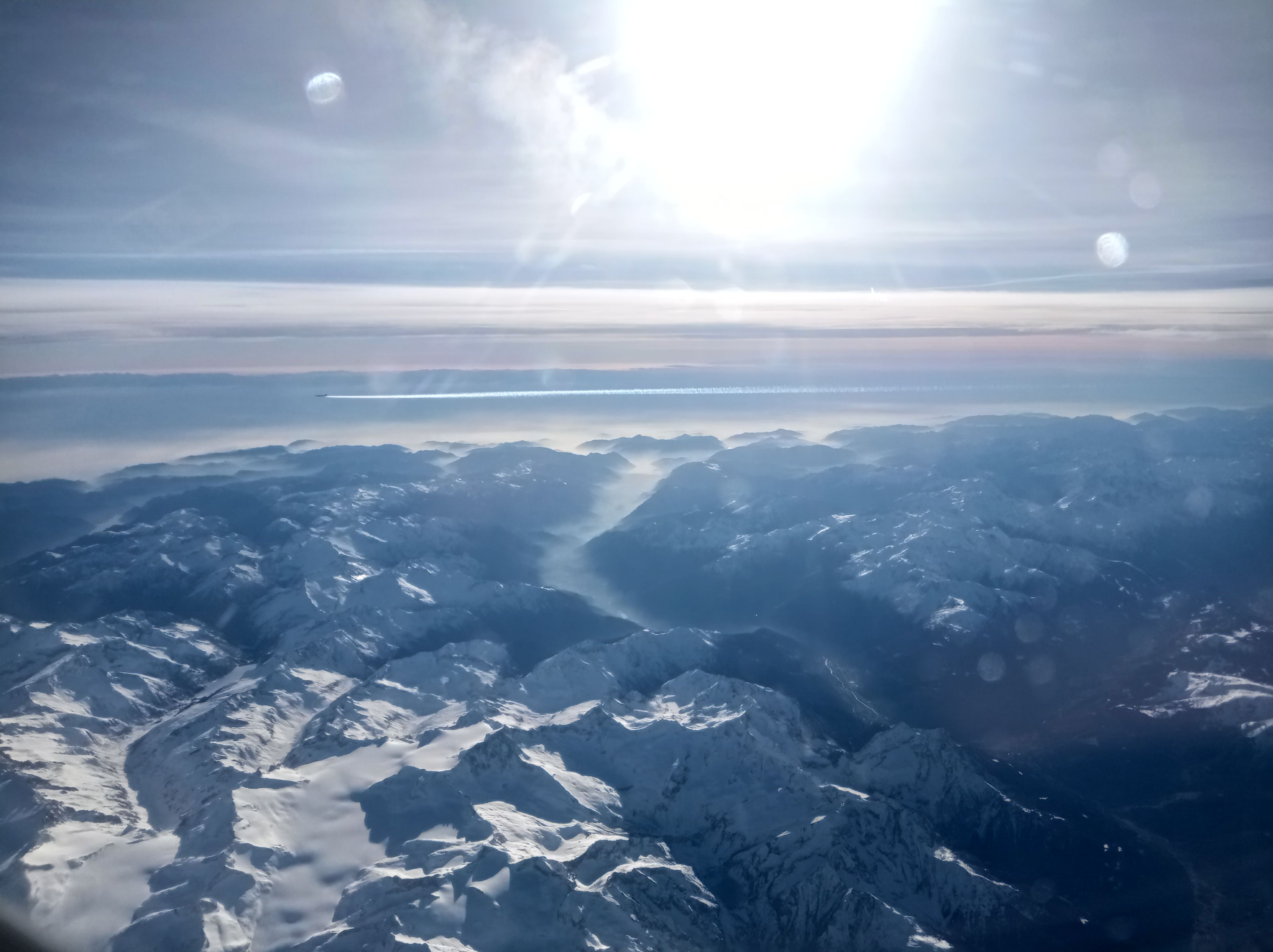 Looking out an aircraft window at picturesque mountains in Europe.