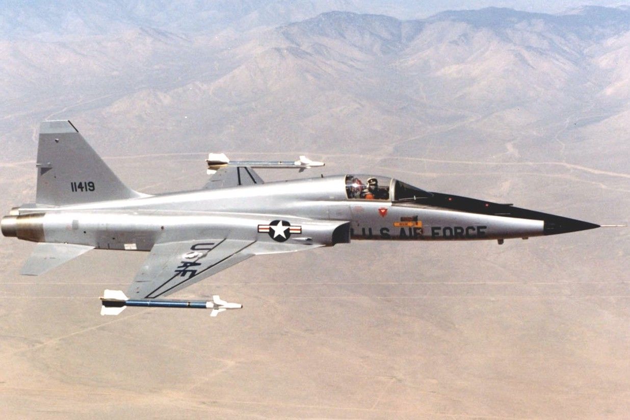 Um Northrop F-5 voando sobre um deserto.