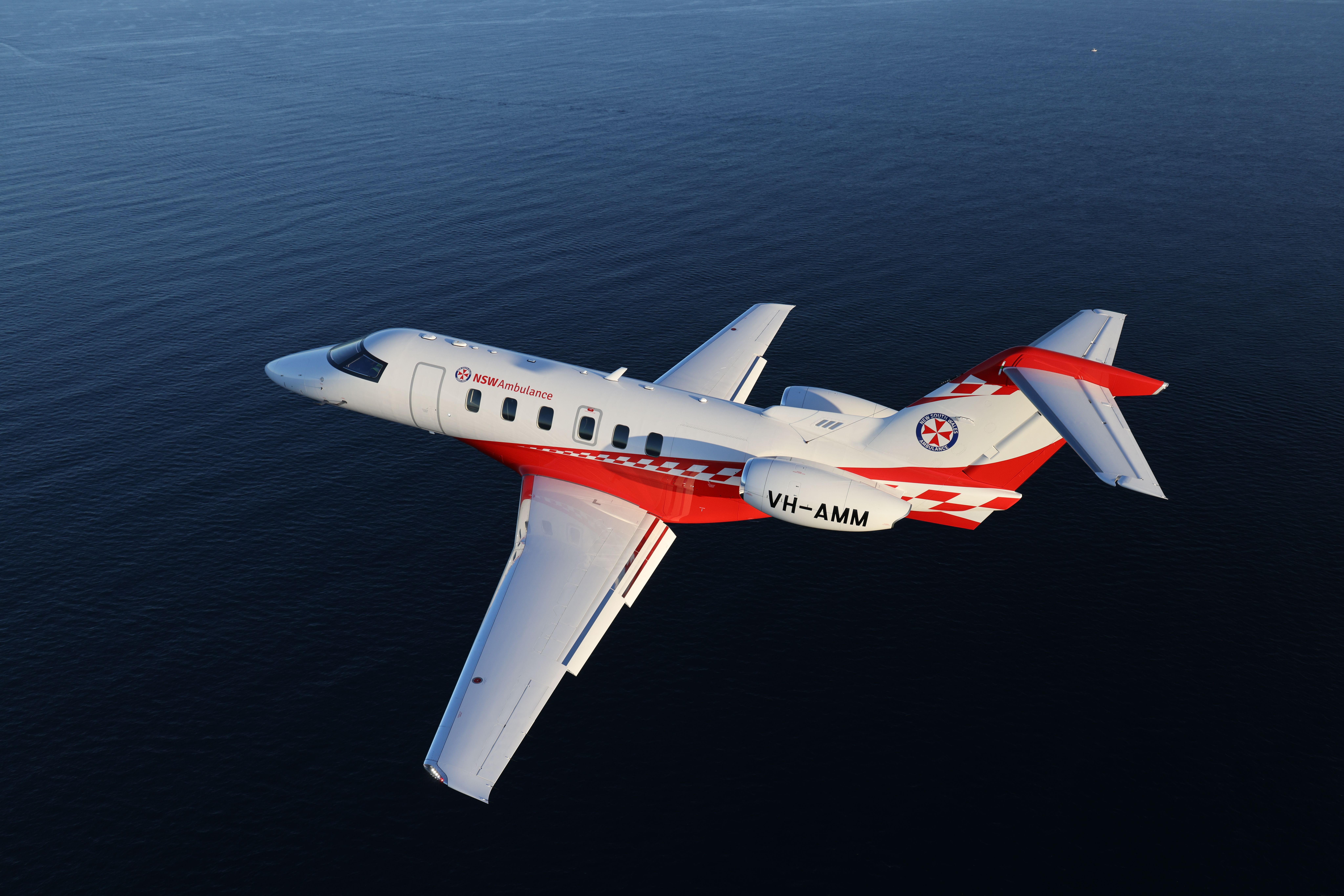 A New South Wales Ambulance Pilatus PC-24 Flying over water.