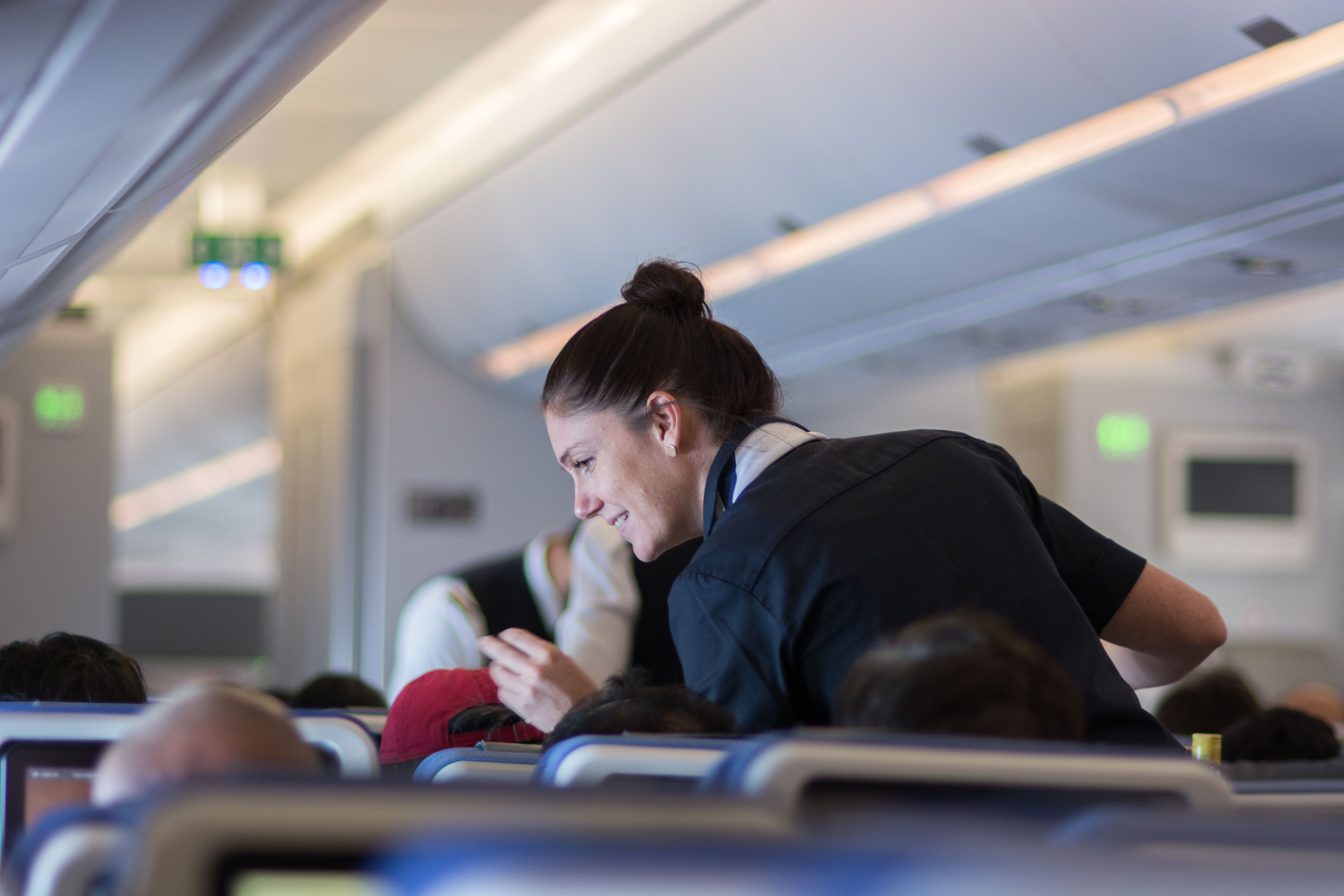 A flight attendant talking with a passenger.