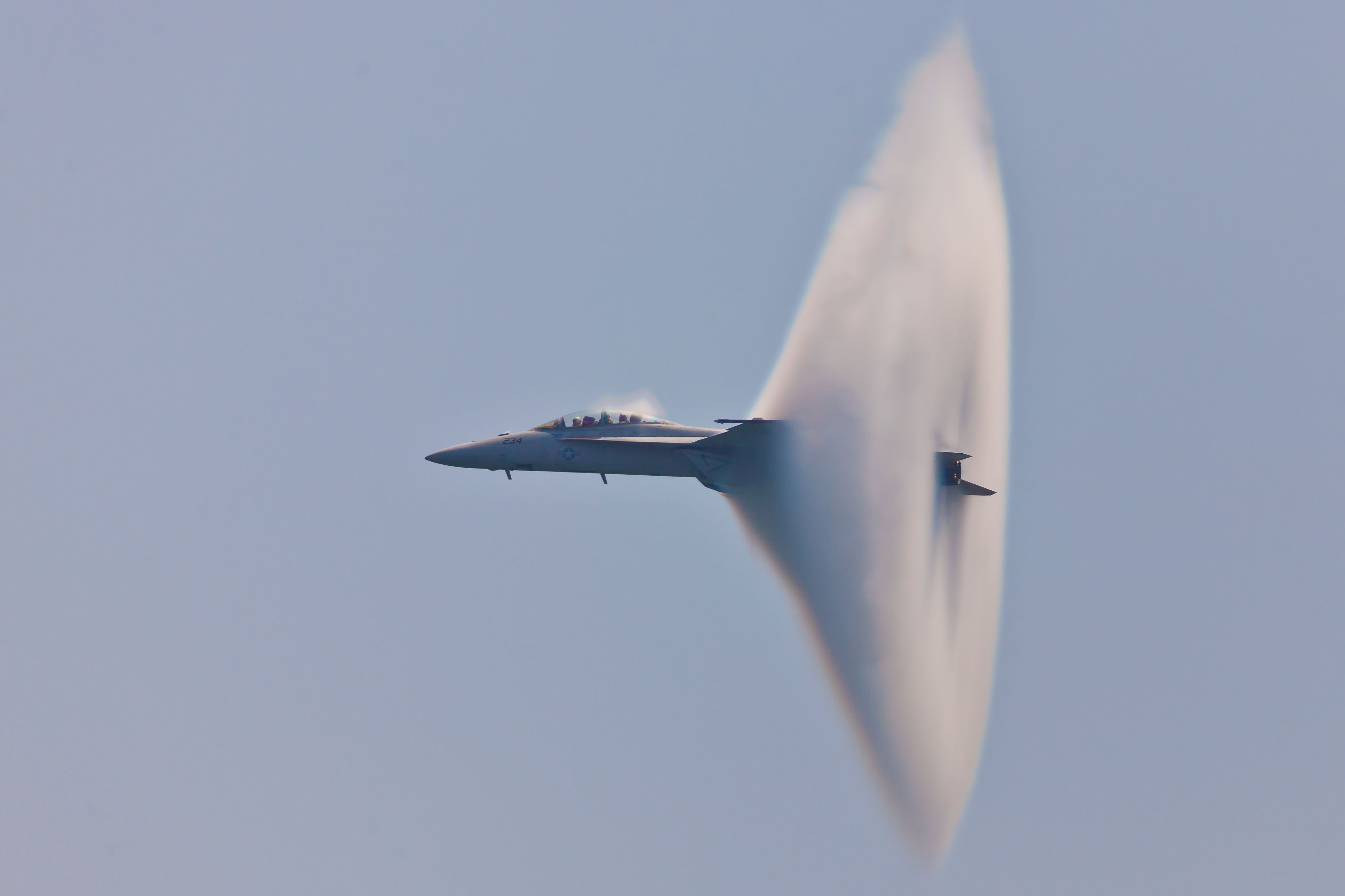 An F-18 Super Hornet with a Mach Cone at the tail.