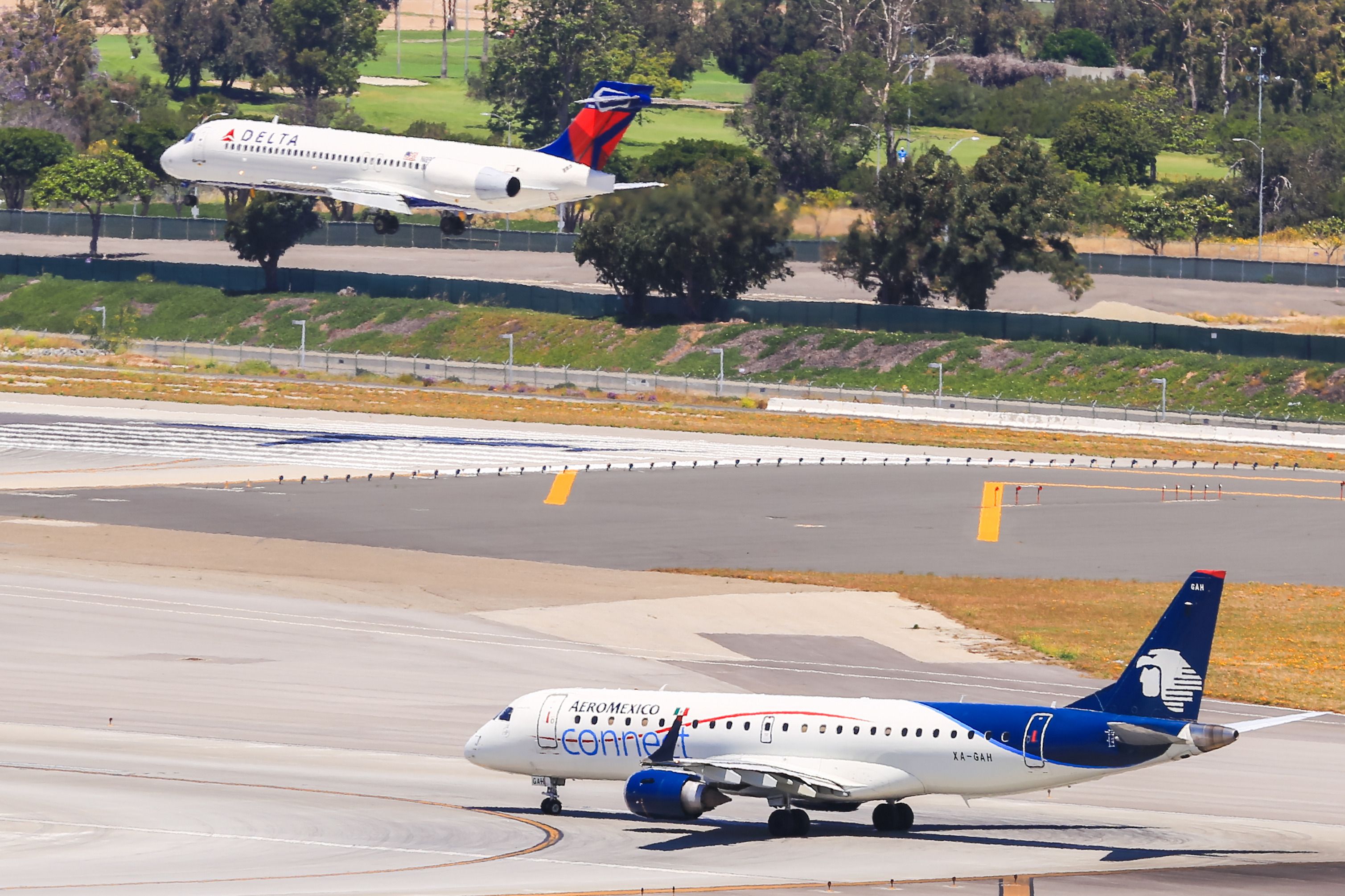 An Aeromexico-Plane (ERJ-190) is waiting for take off at the Los Angeles International Airport (LAX). In the background a Delta plane lands.