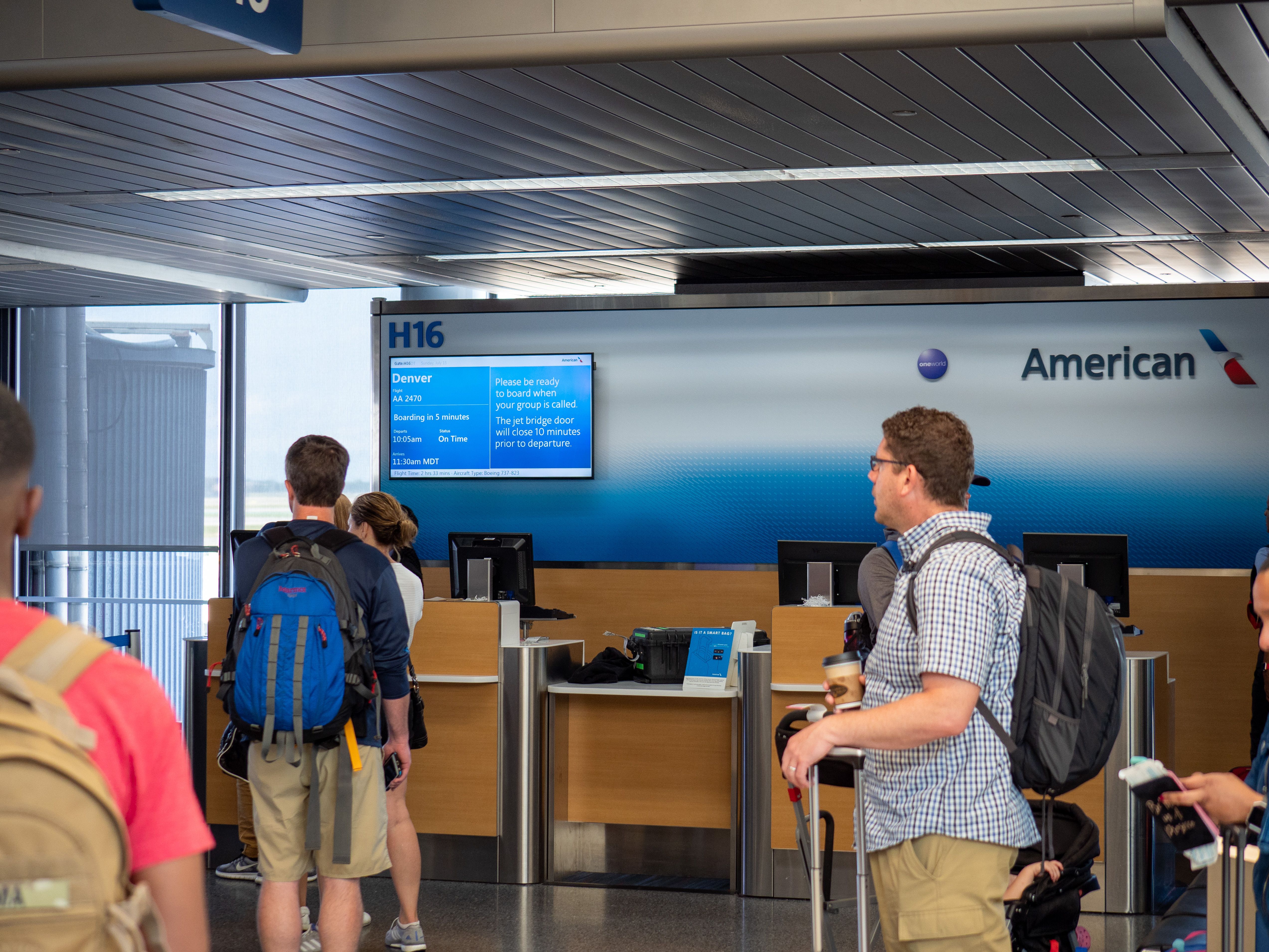 Several passengers waiting at an American Airlines Boarding Gate in an airport.