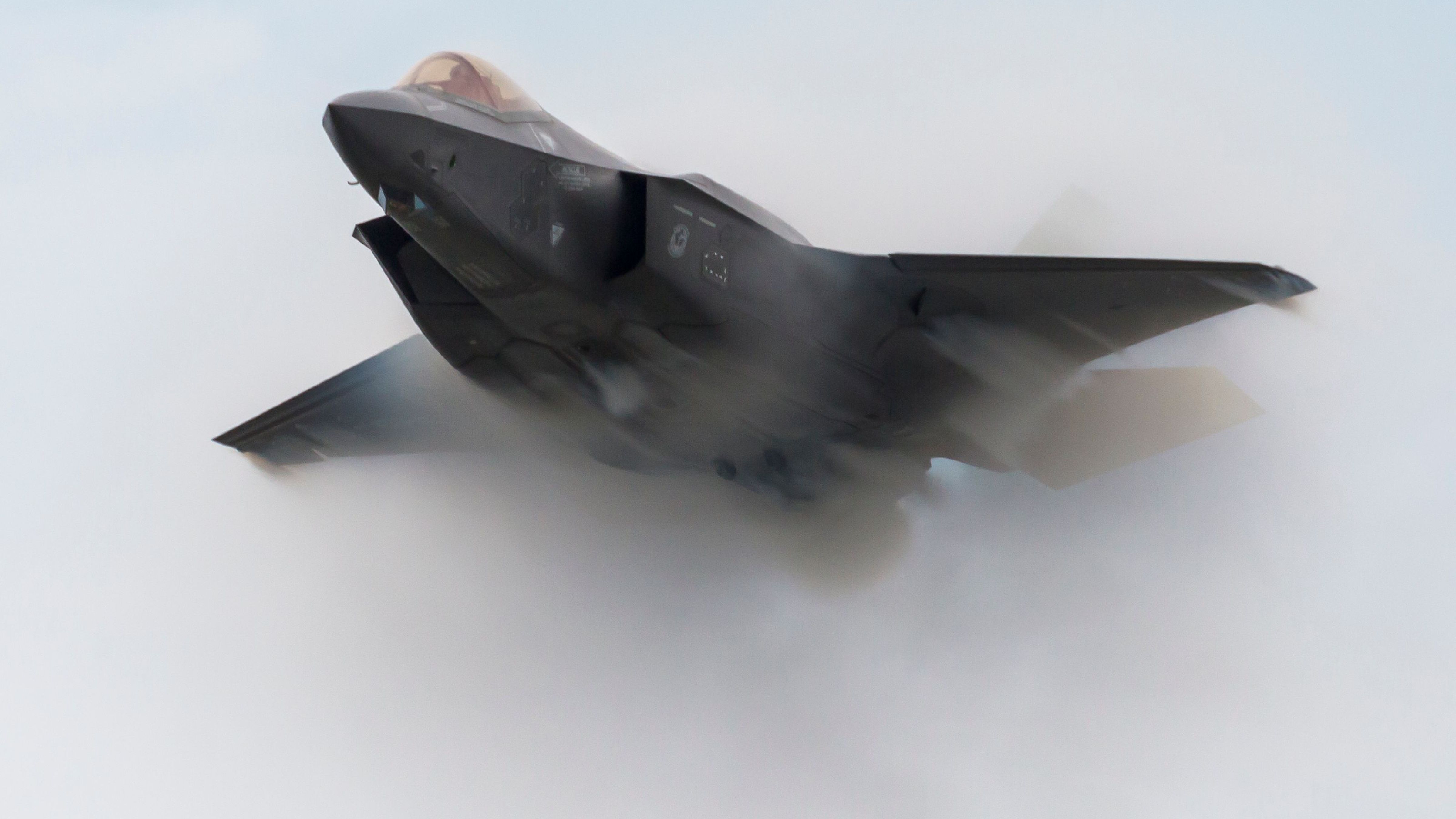 An F-35 flying through smoke during an aerial performance.