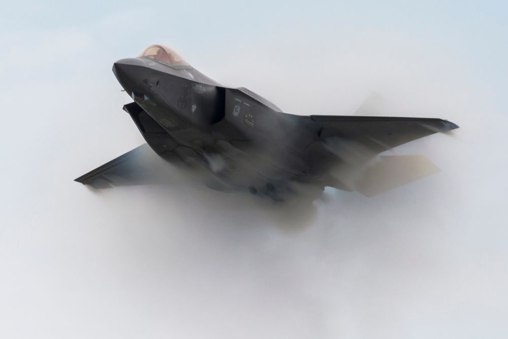 An F-35 flying through smoke during an aerial performance.