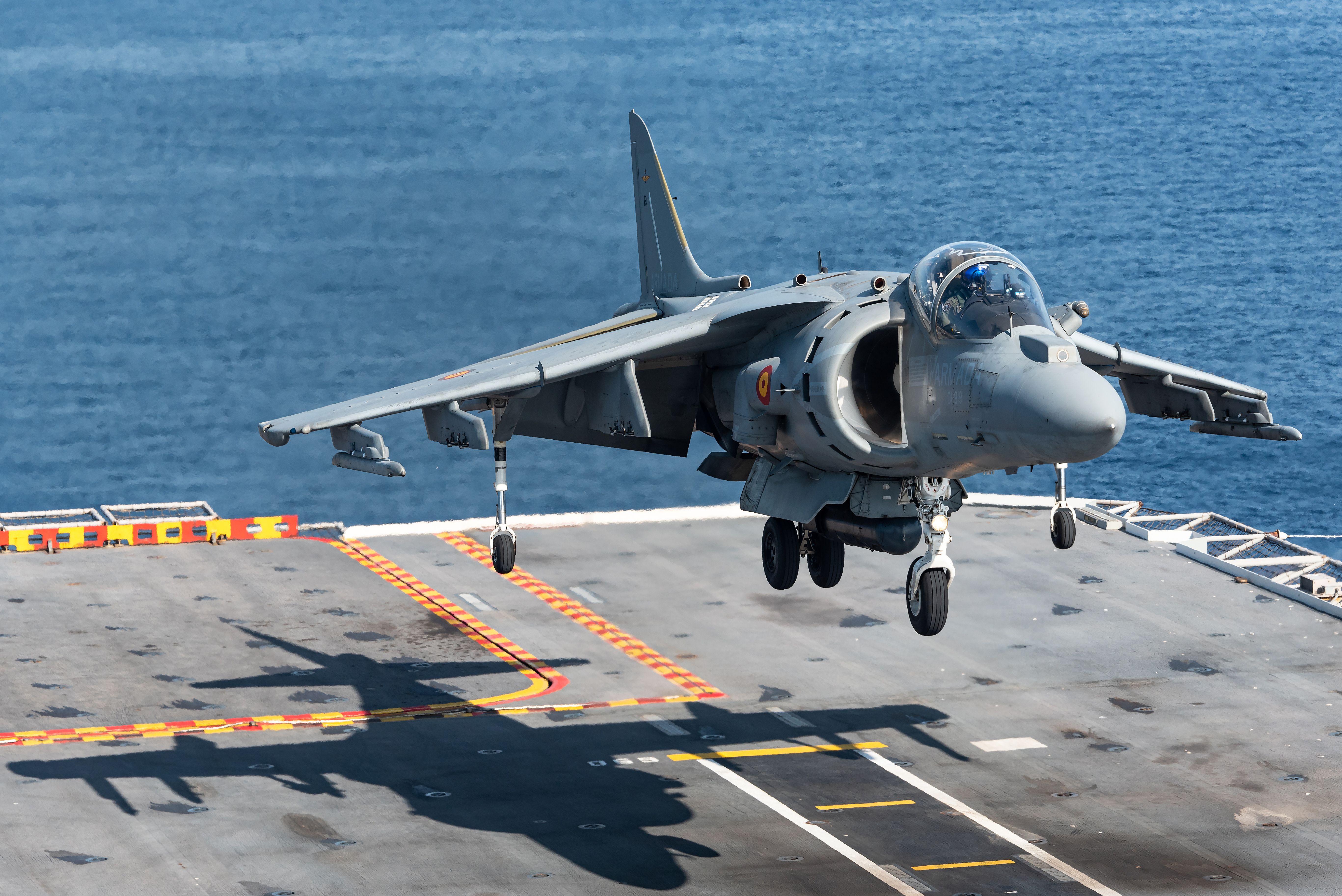 A Spanish Navy Harrier fighter jet landing on an aircraft carrier. 