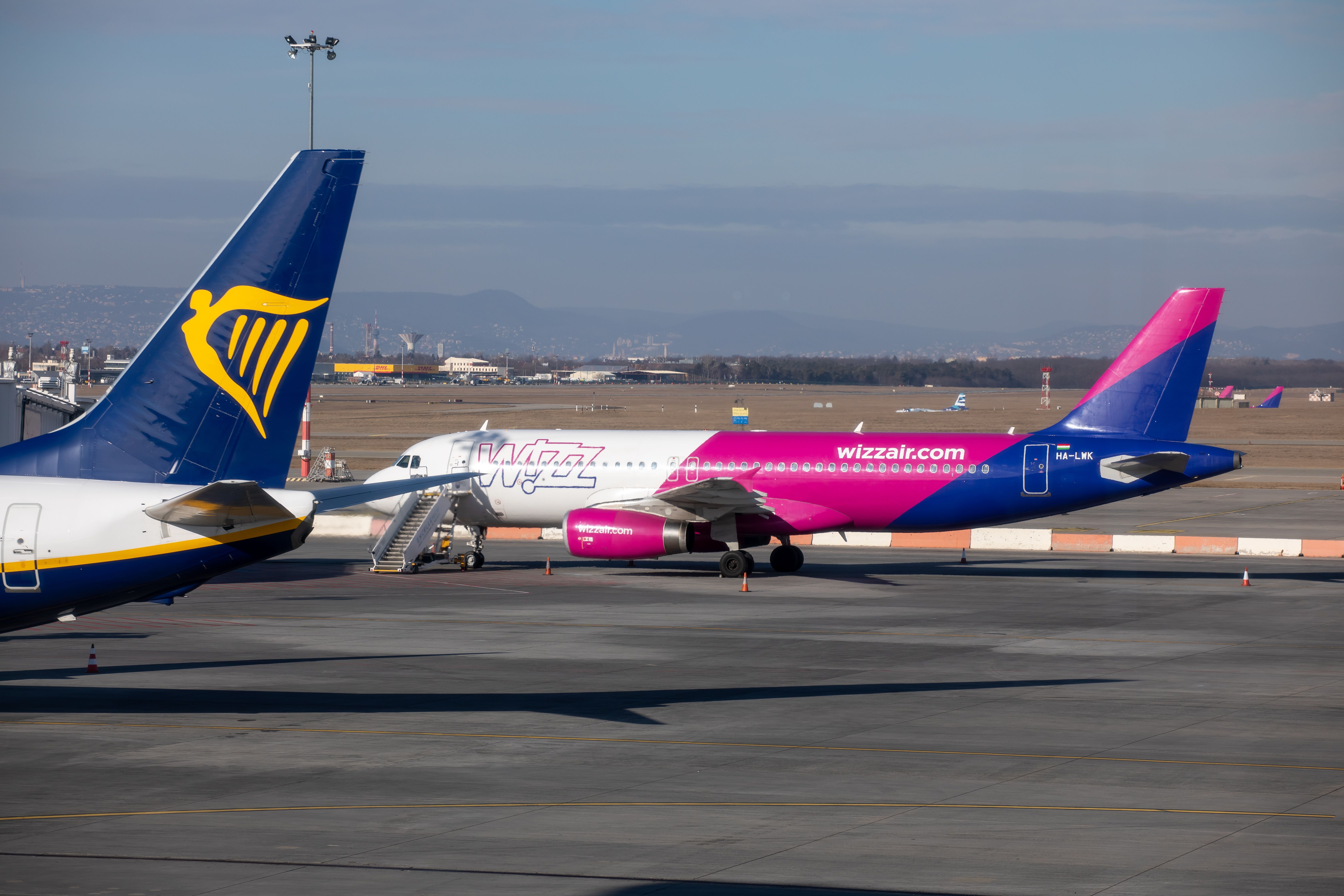S Wizz Air Airbus A320 Parked on an airport apron With a Ryanair aircraft Tail seen In the Foreground.