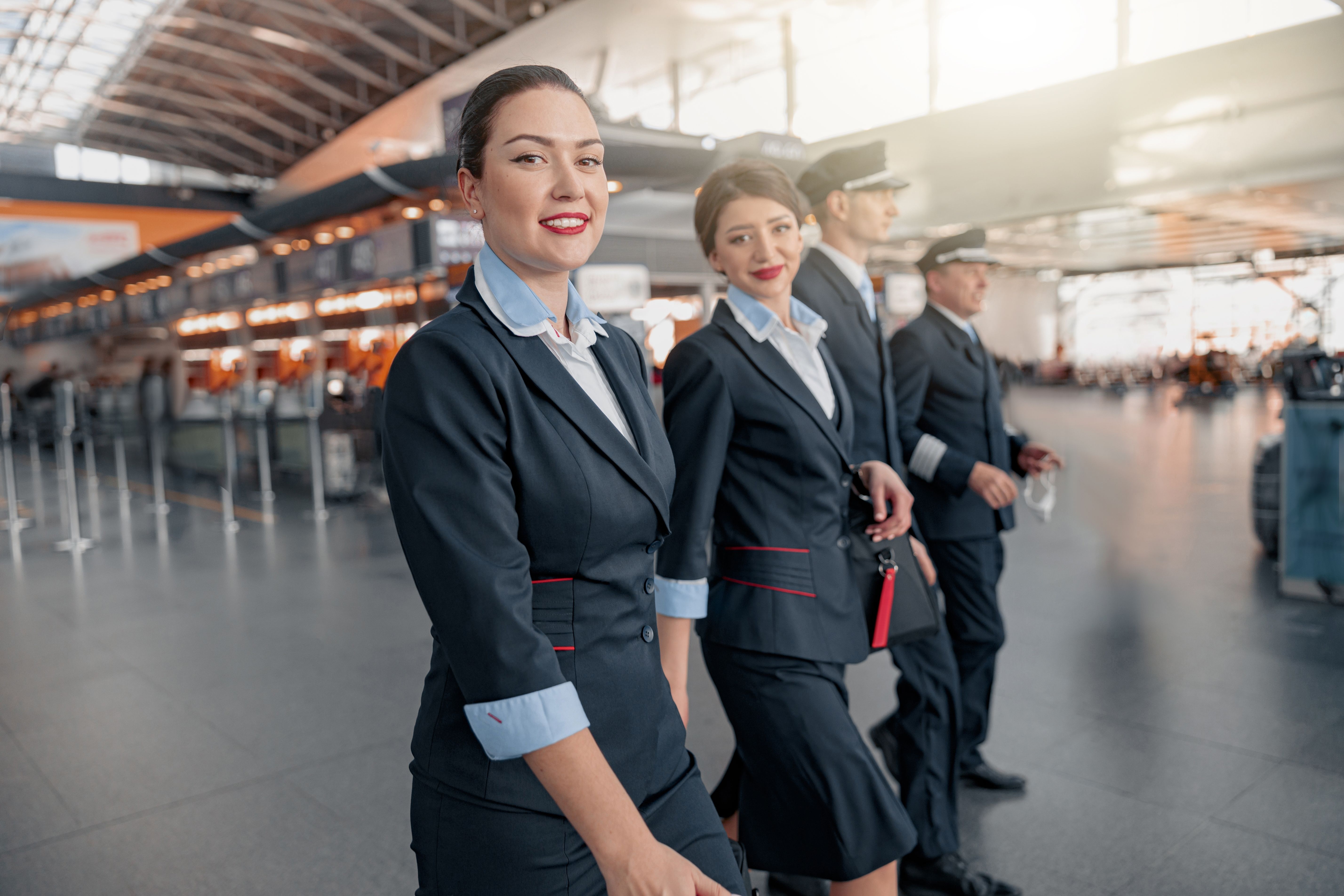 Multiple Pilots and cabin crew walking in an airport terminal.