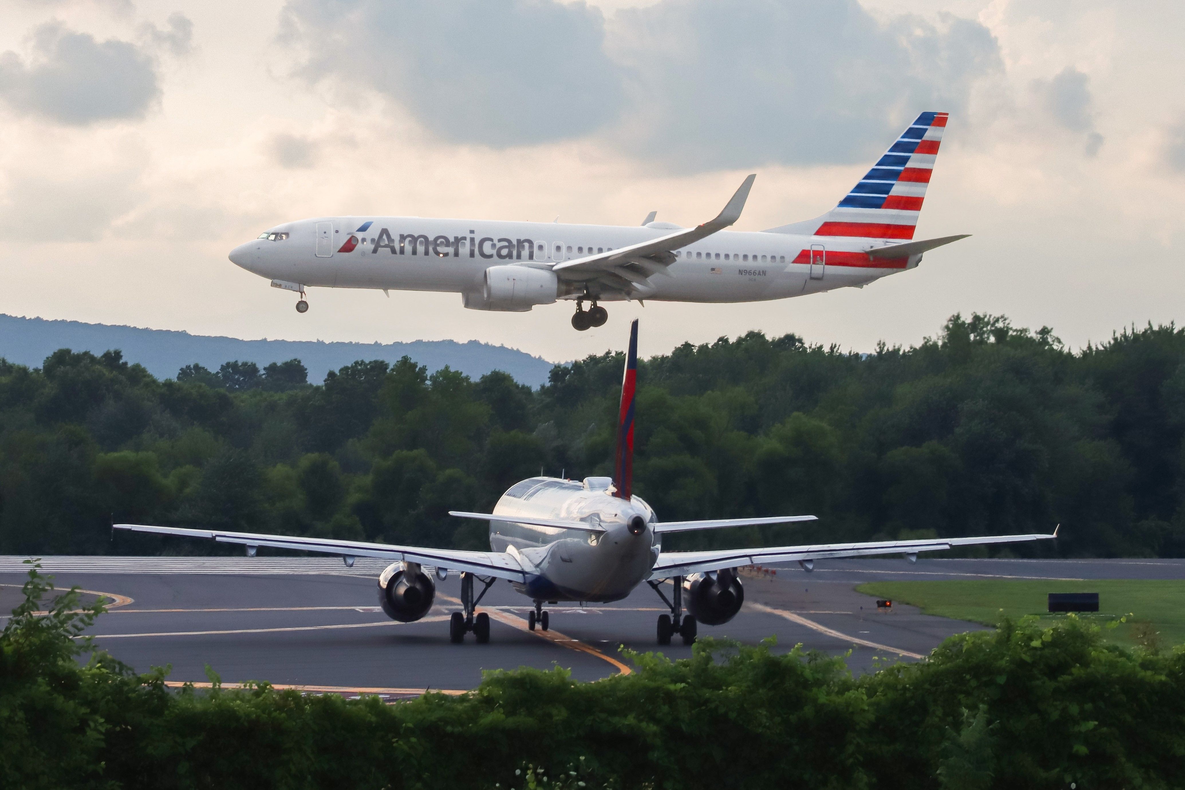 An American Airlines Boeing 737 Landing While A Delta Air Lines Aircraft Waits on the Apron.