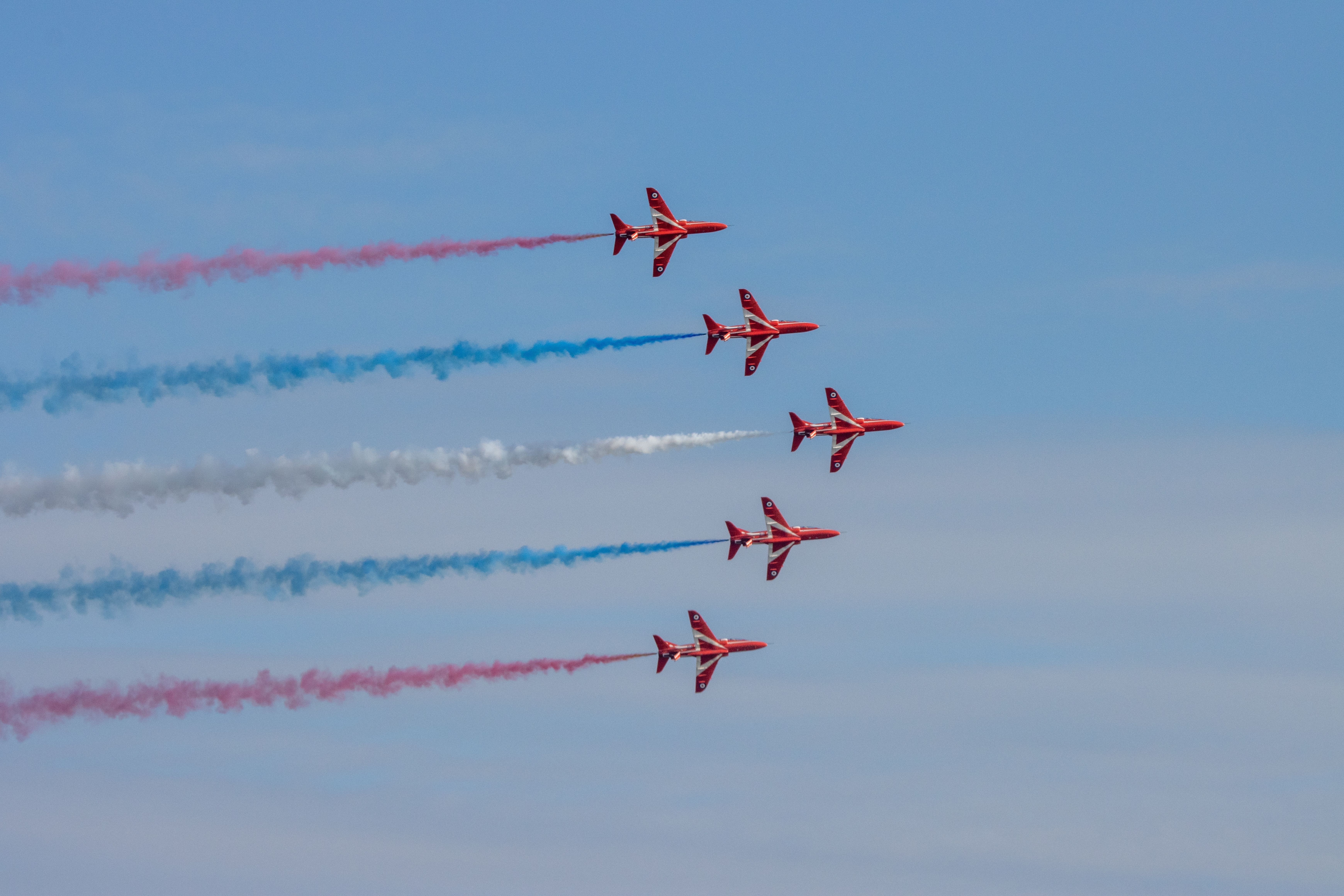 Five Red Arrows BAE Hawks With Tricolor Smoke Trails Flying in the sky.