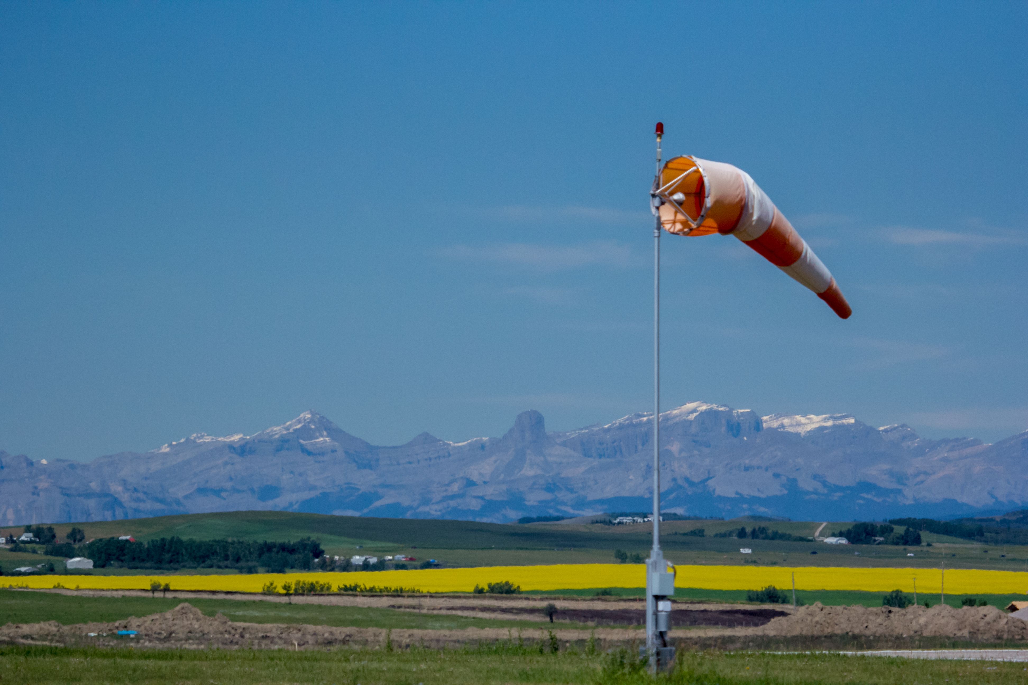 A windsock with a field and mountains in the background.
