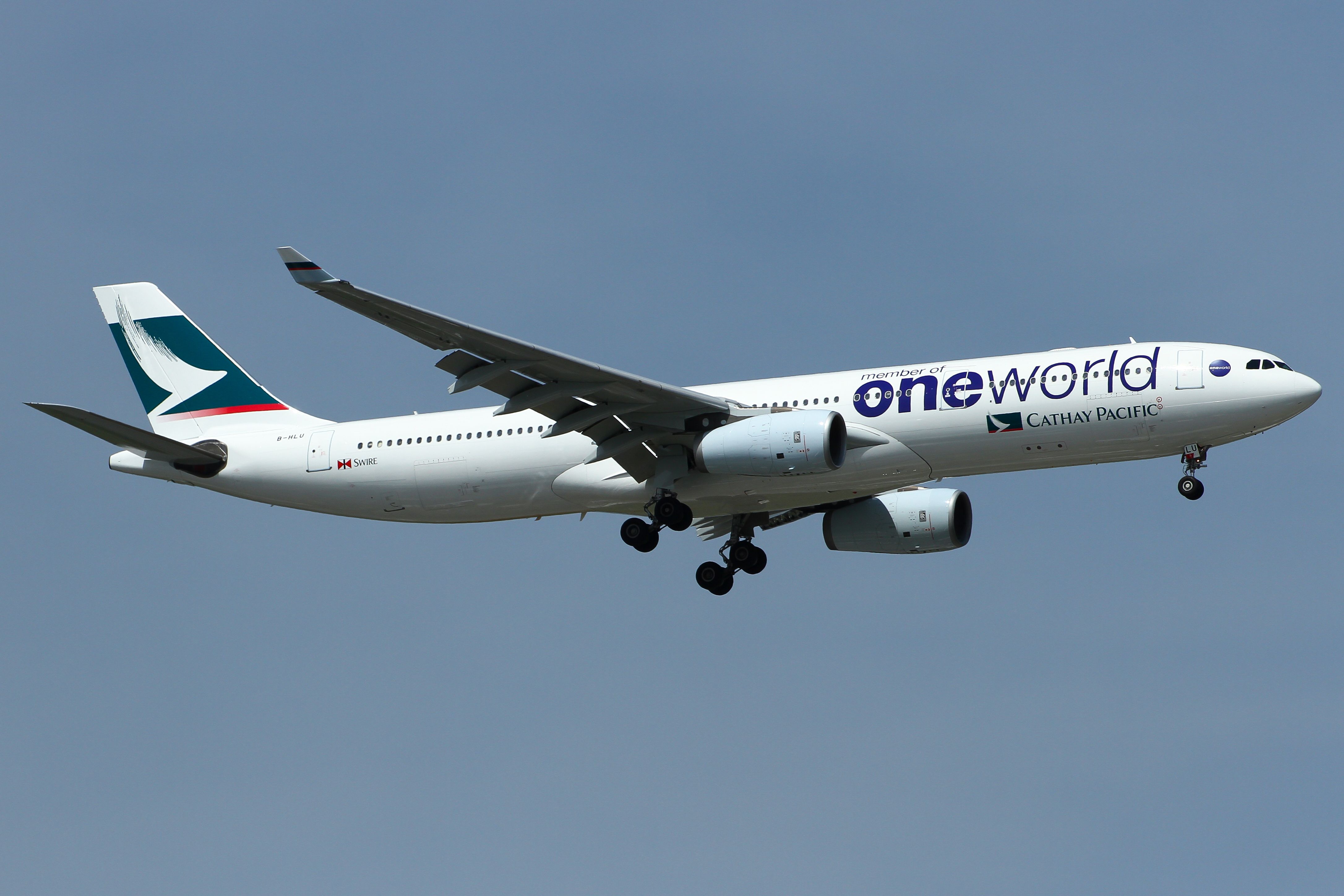 A Cathay Pacific Airbus A330-300 in oneworld livery flying in the sky.