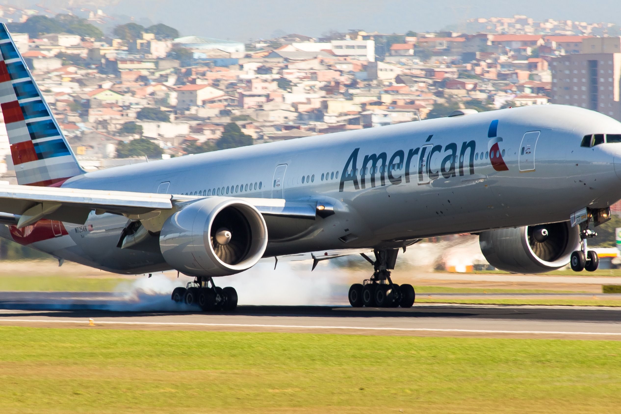 An American Airlines Boeing 777-300ER landing on a runway.