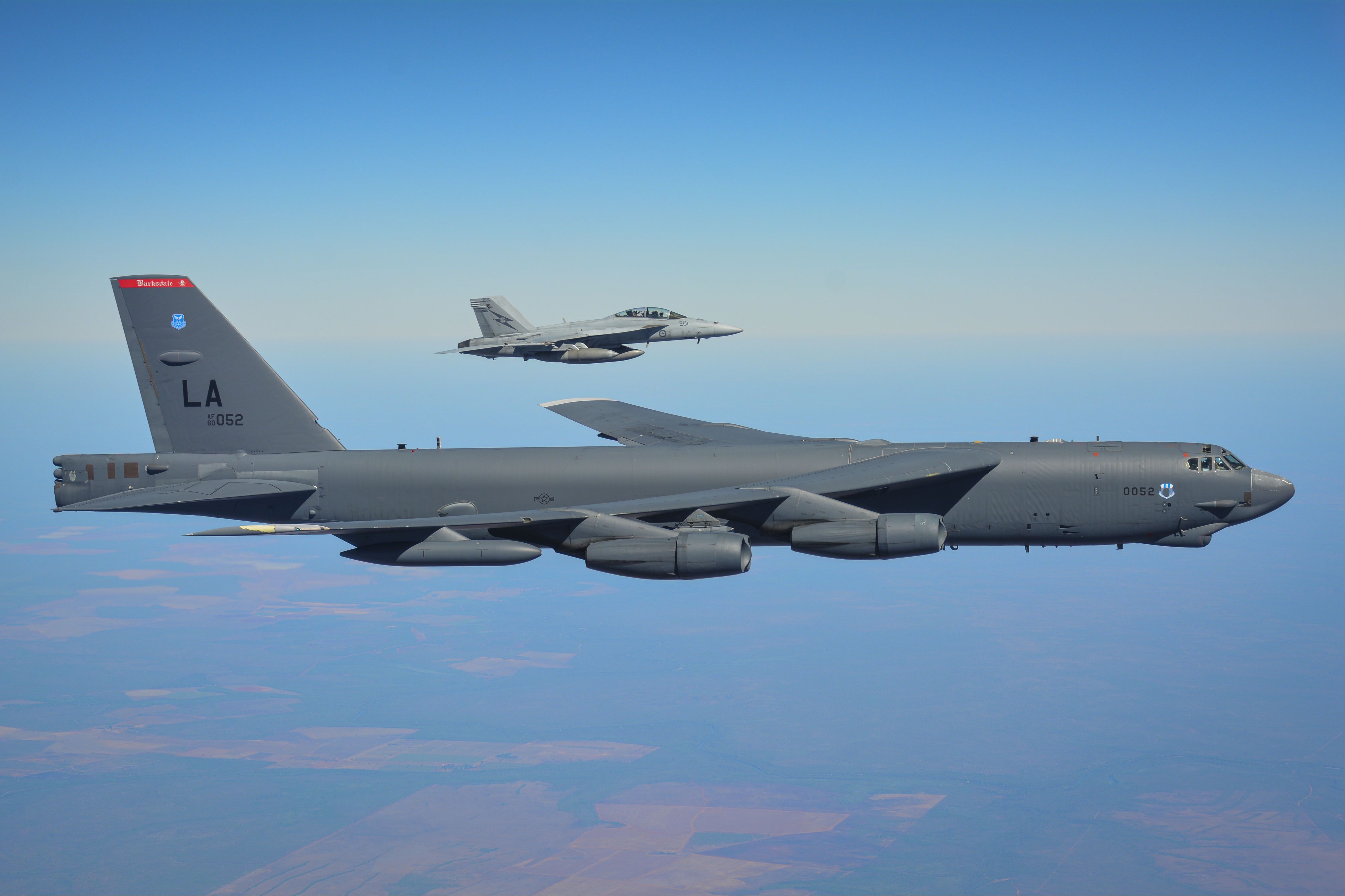 A Boeing B-52 flying in formation with a fighter jet.