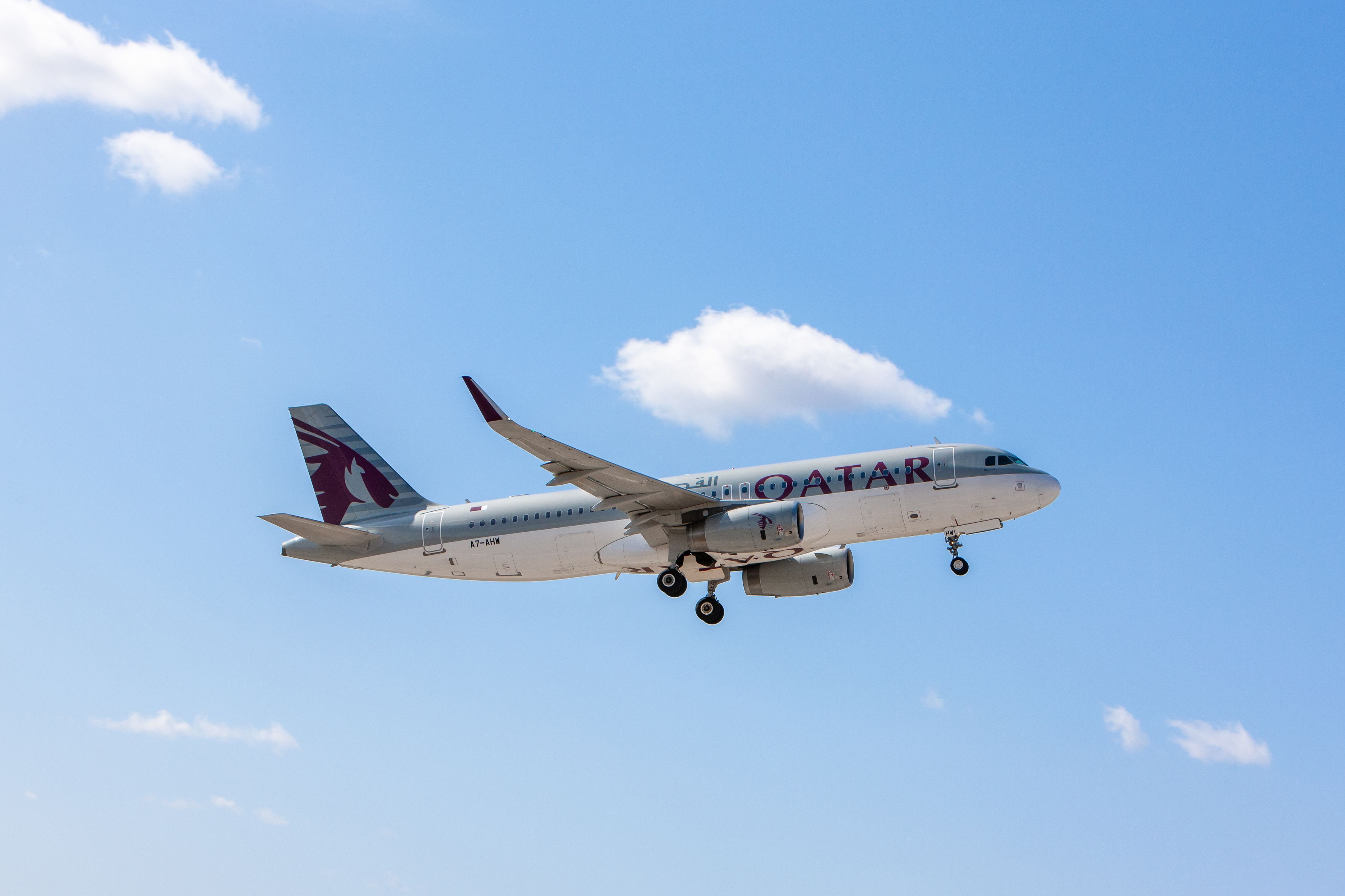 A Qatar Airways Airbus A320 flying in a blue sky